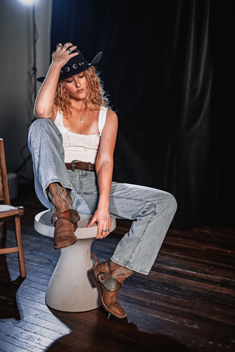 Artistic shots of person in overalls and boots on dark wooden floor.