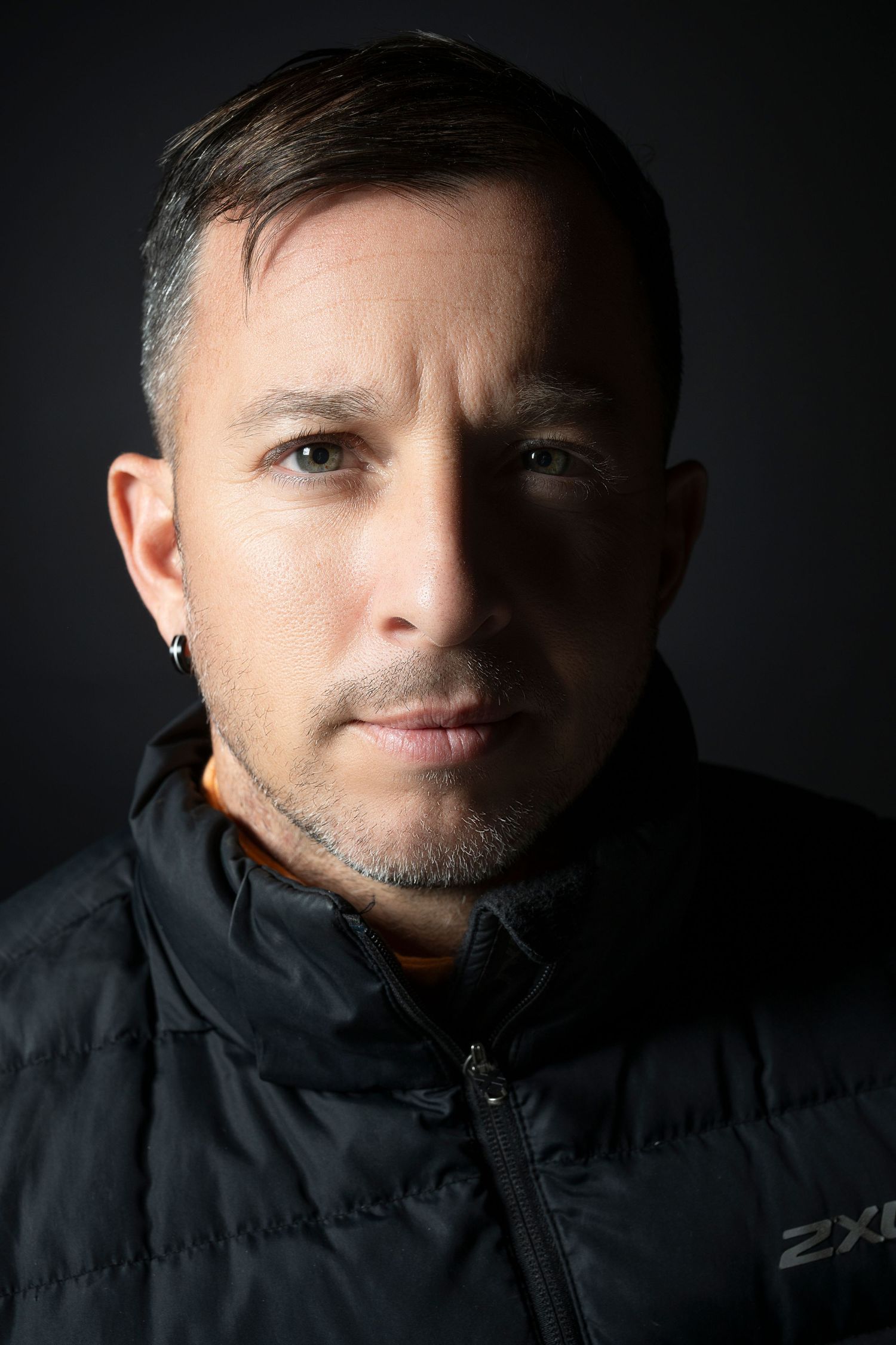 Close-up portrait of a person in black vest with dramatic side lighting.