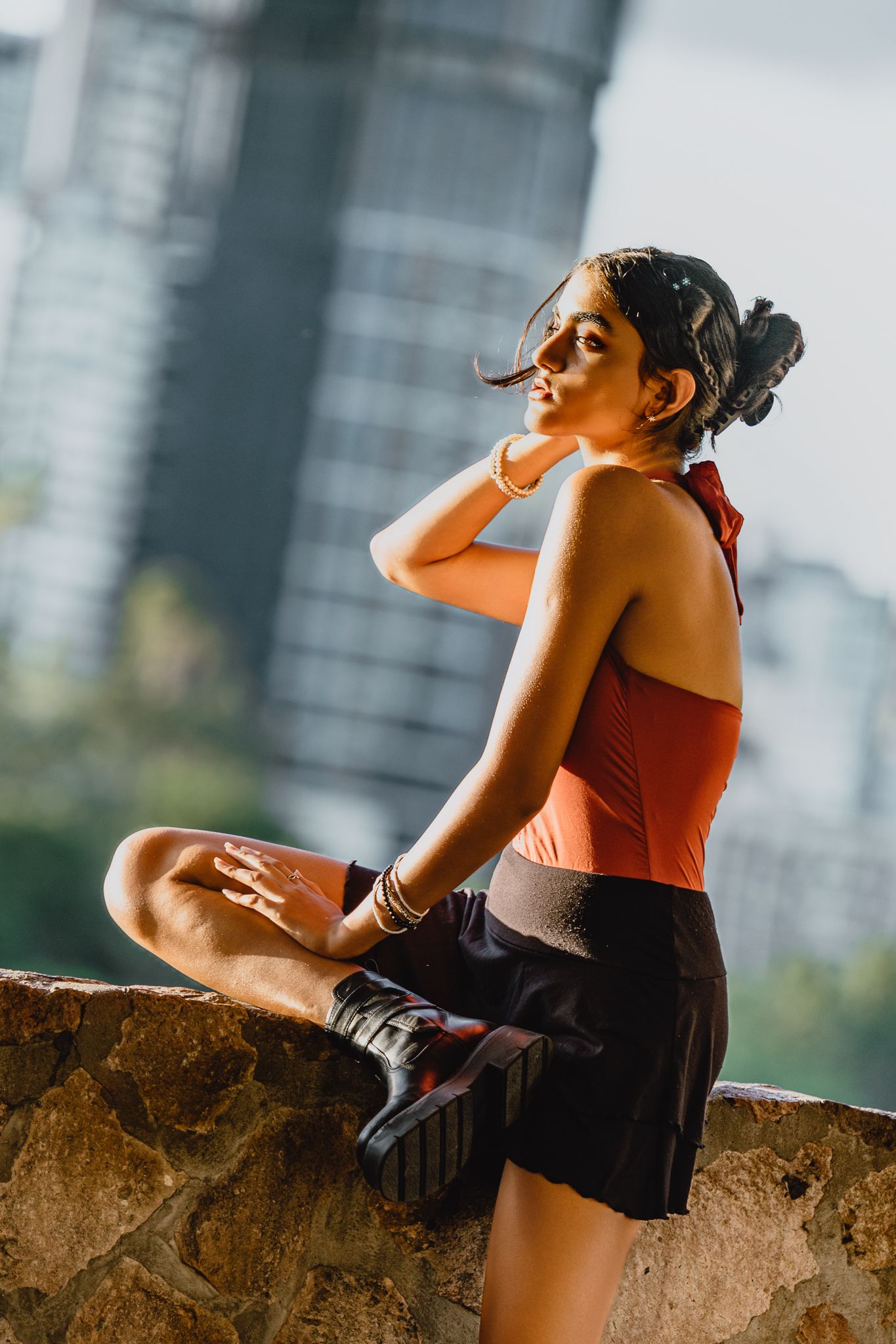 Athletic figure in workout attire poses on stone wall with cityscape behind.