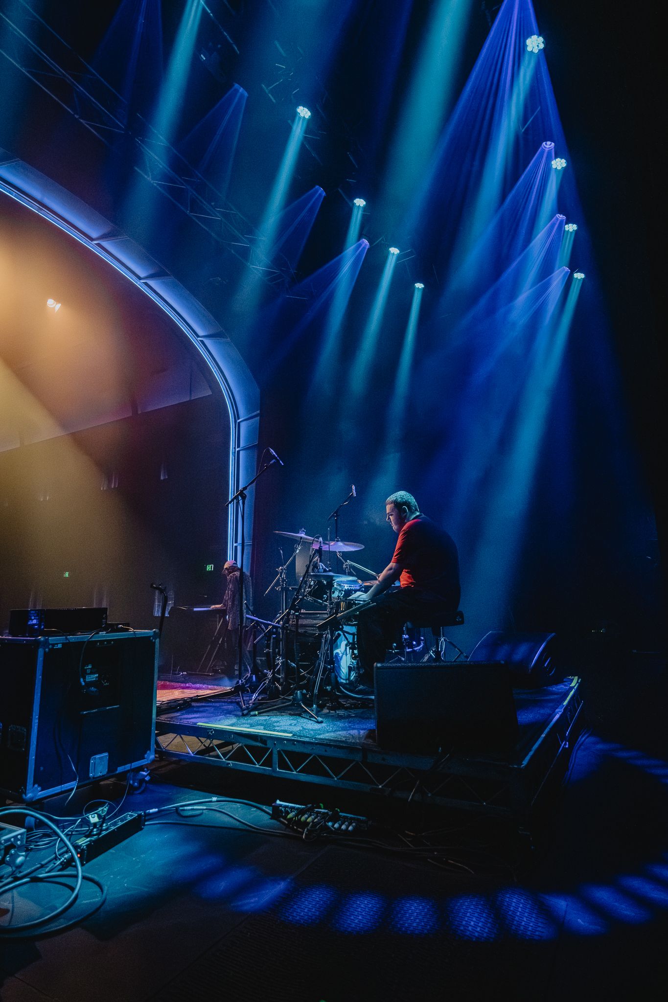 Concert stage with dramatic blue spotlights creating beams through atmospheric haze.