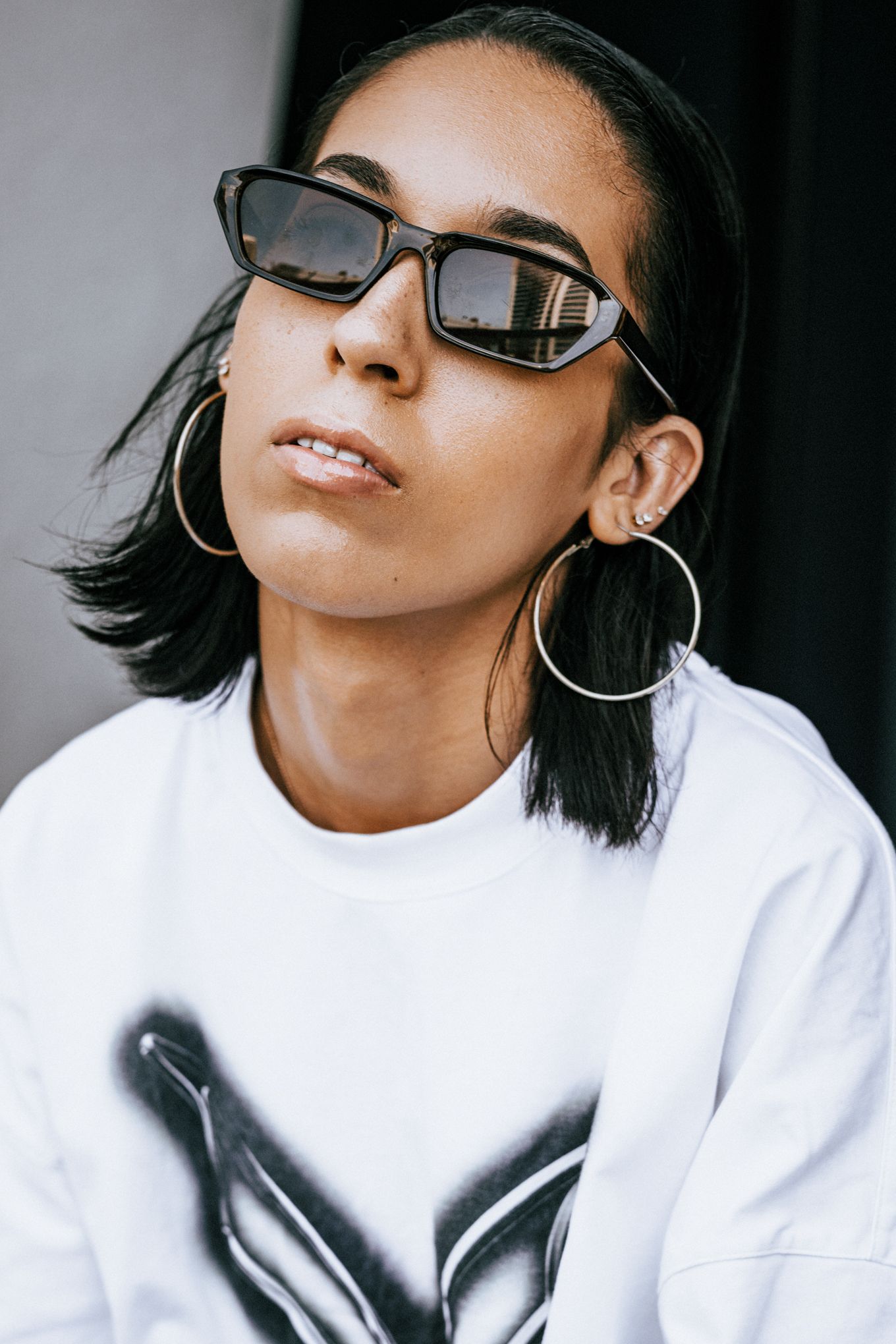 Portrait series featuring white sweatshirt and stylish sunglasses with minimalist backdrop.
