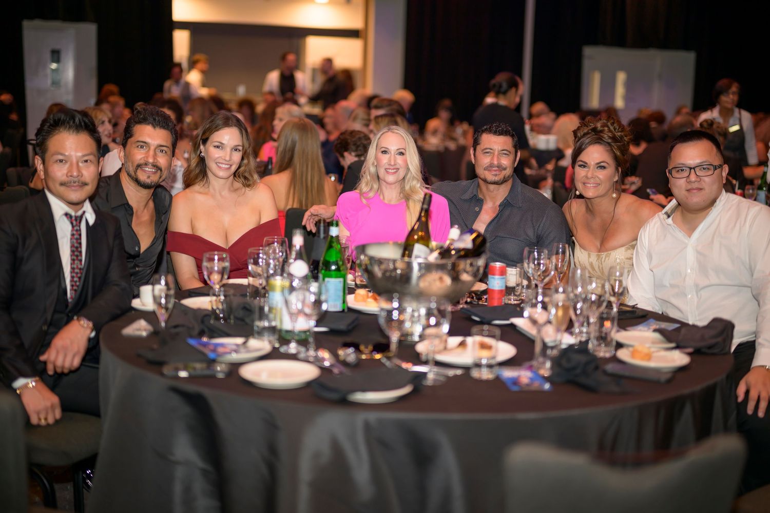 Group of attendees seated at a round table during a formal black-tie gala event.