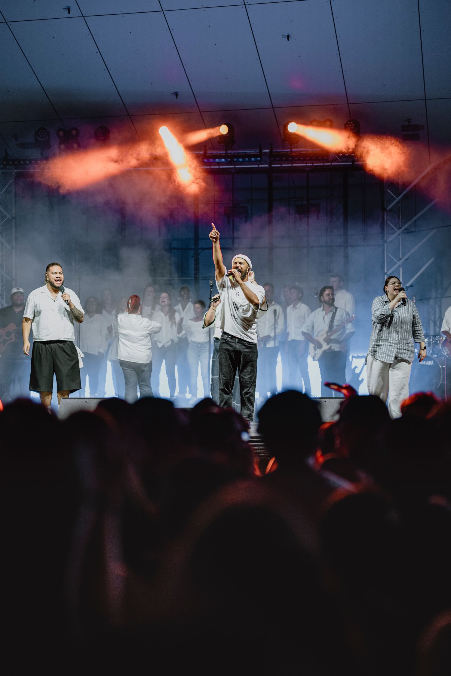Group performance on stage with dramatic orange lighting and smoke effects.