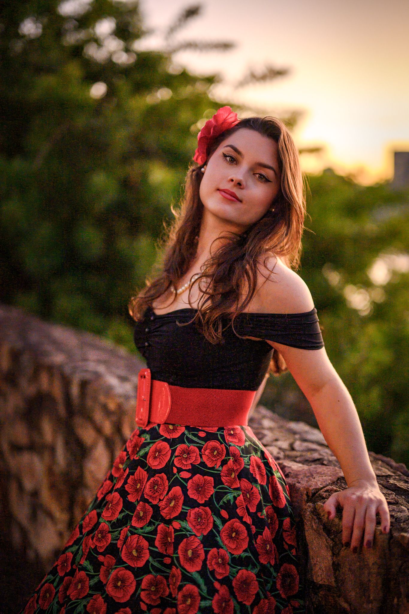 Portrait of woman in red floral dress posing at sunset.