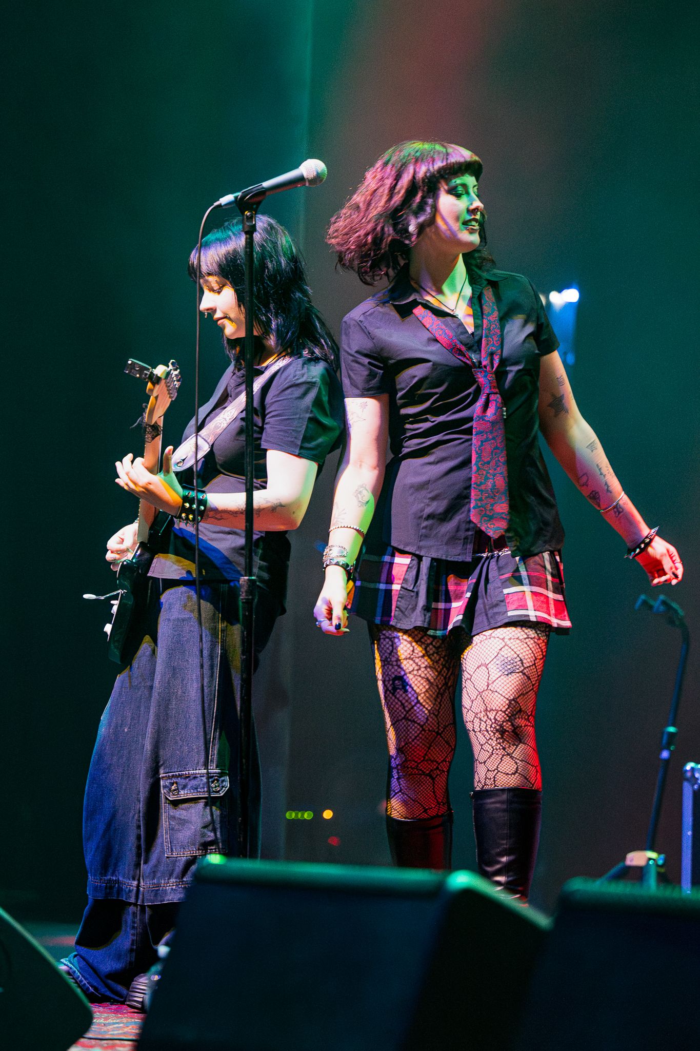 Two musicians performing on stage with colorful lighting effects.