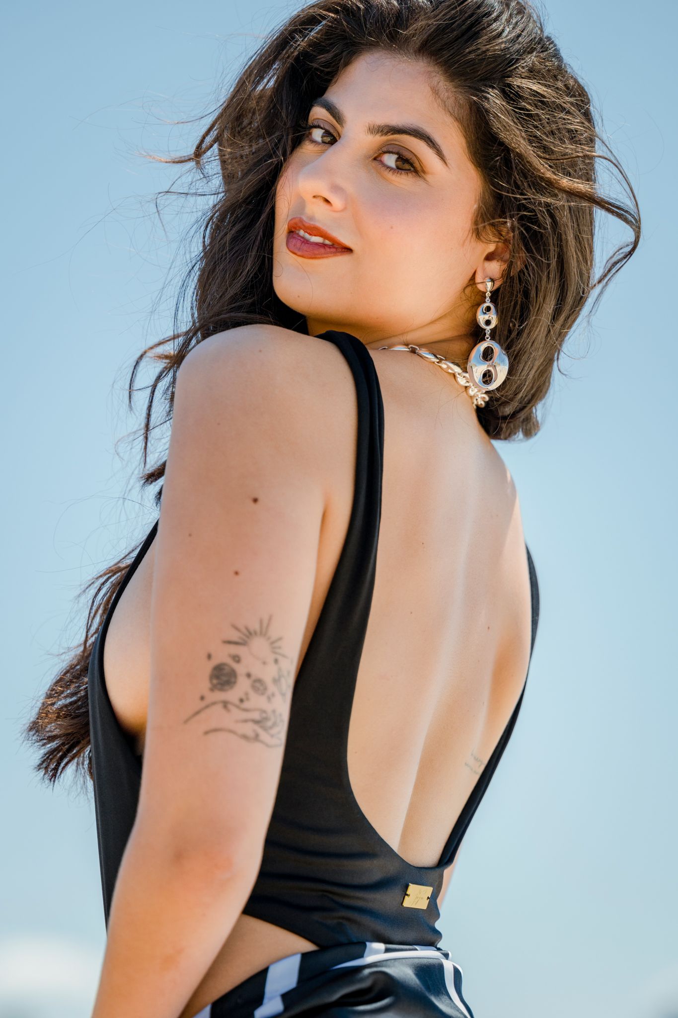 Back view portrait showing black swimwear and natural lighting at beach setting.