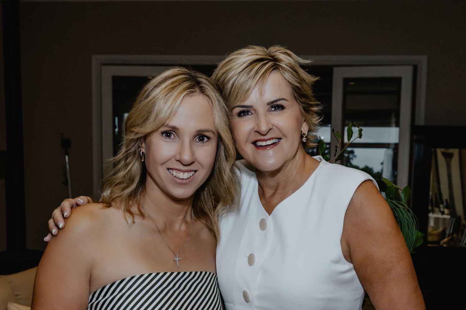 Two women posing together at an elegant evening event.