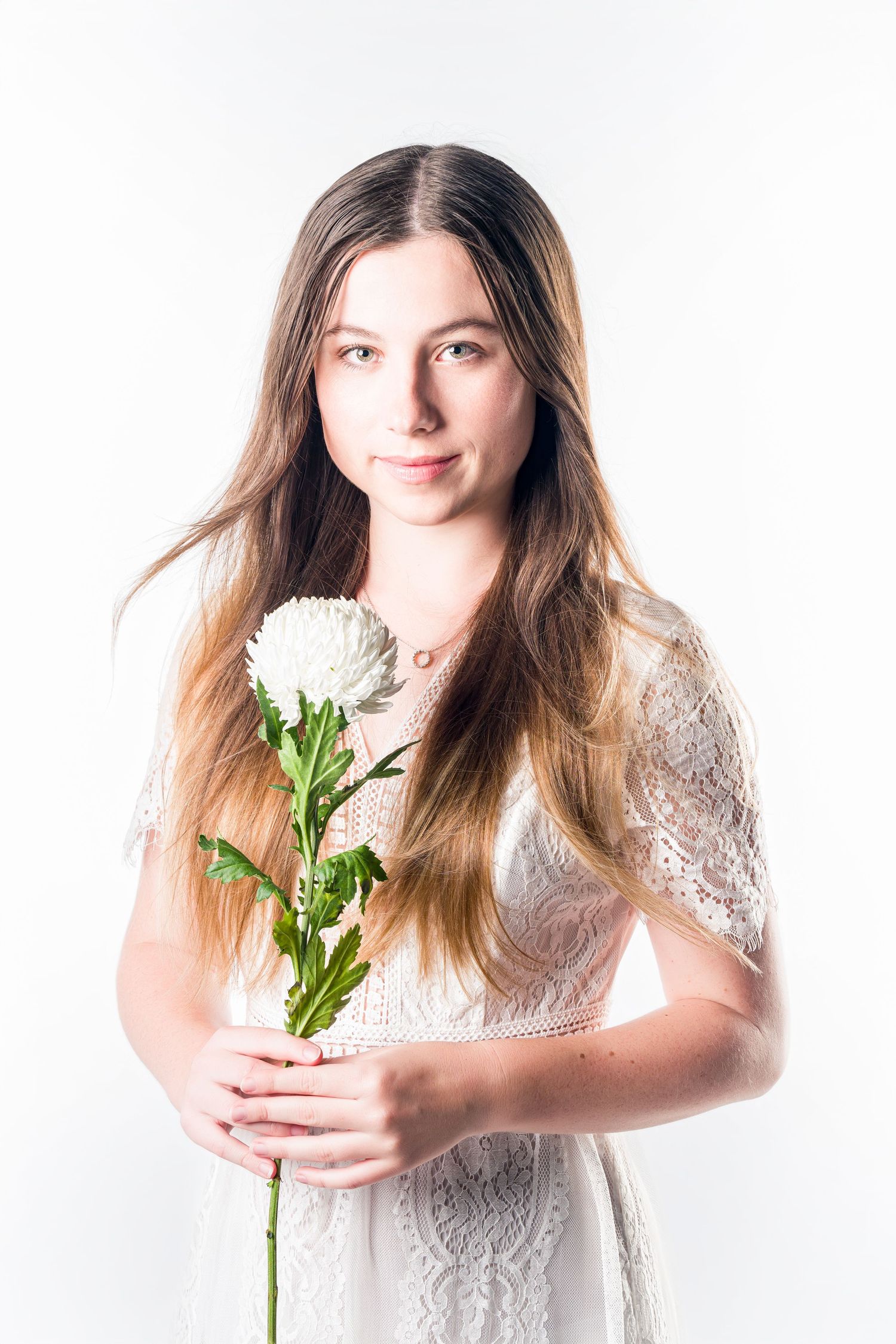 Portrait series against white background holding white flowers in lace dress.