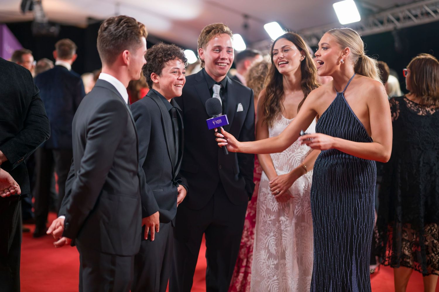 Formal group conversation during awards show red carpet event.