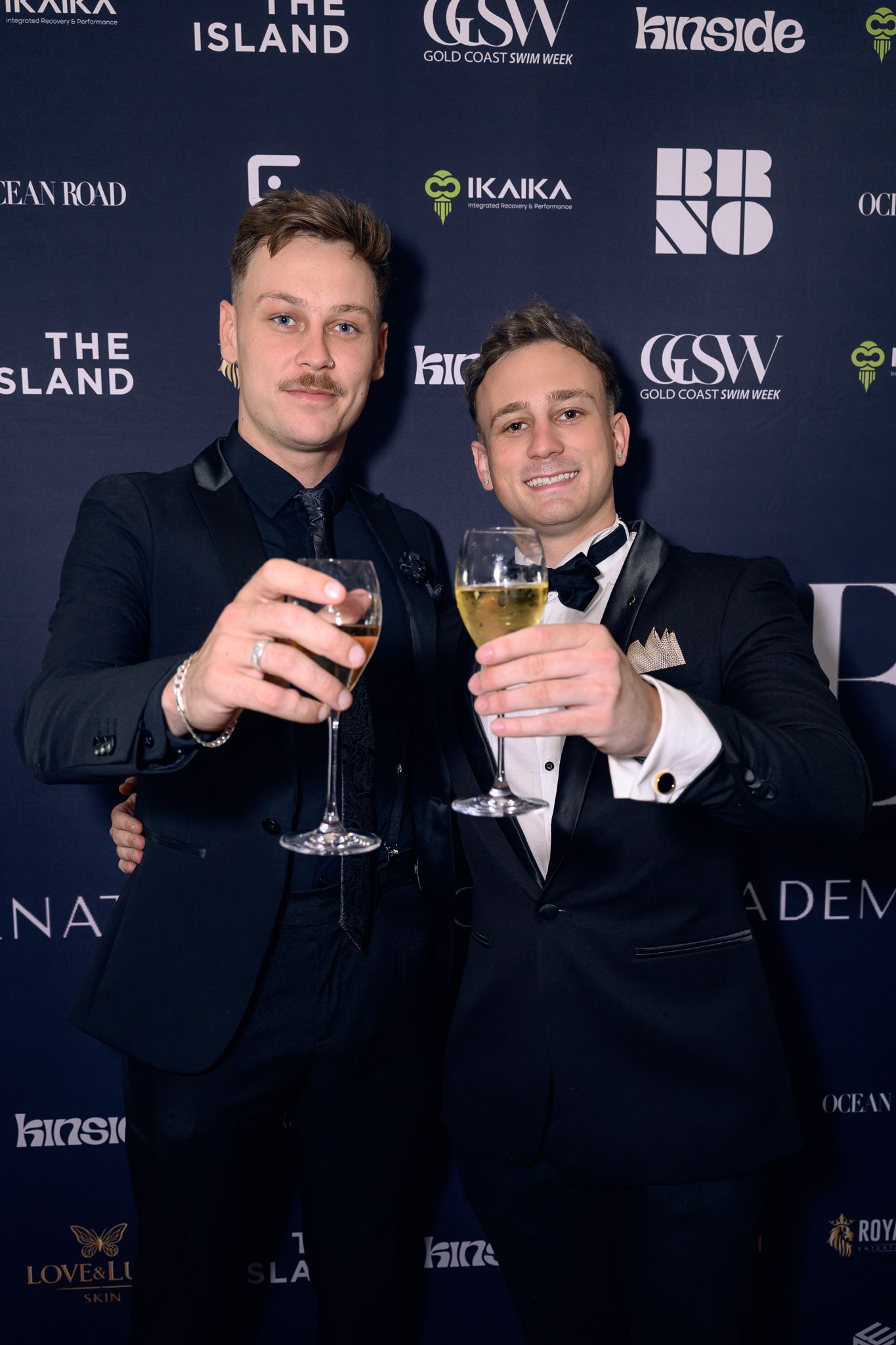 Two people in formal attire toasting with wine glasses at upscale event.