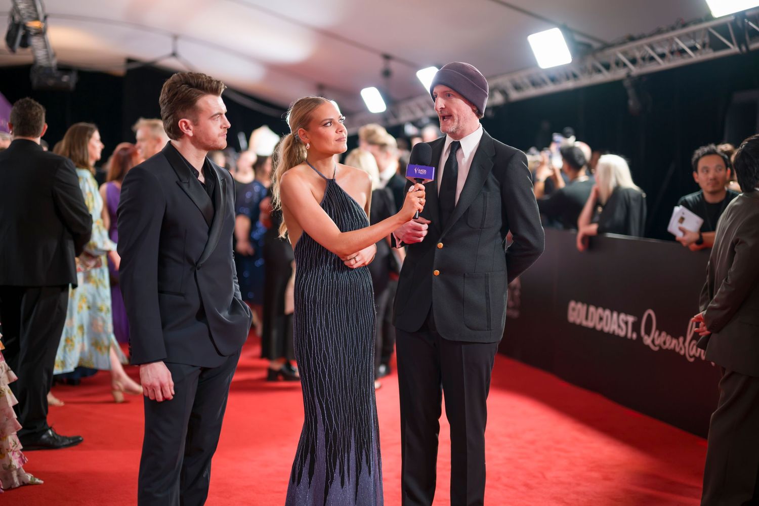 Formal conversation between guests on red carpet at awards ceremony.