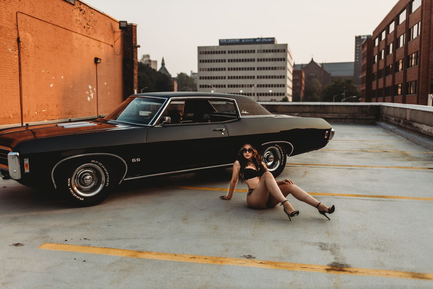 Classic black Lincoln Continental lowrider car parked in a parking garage with custom hydraulic suspension setup.