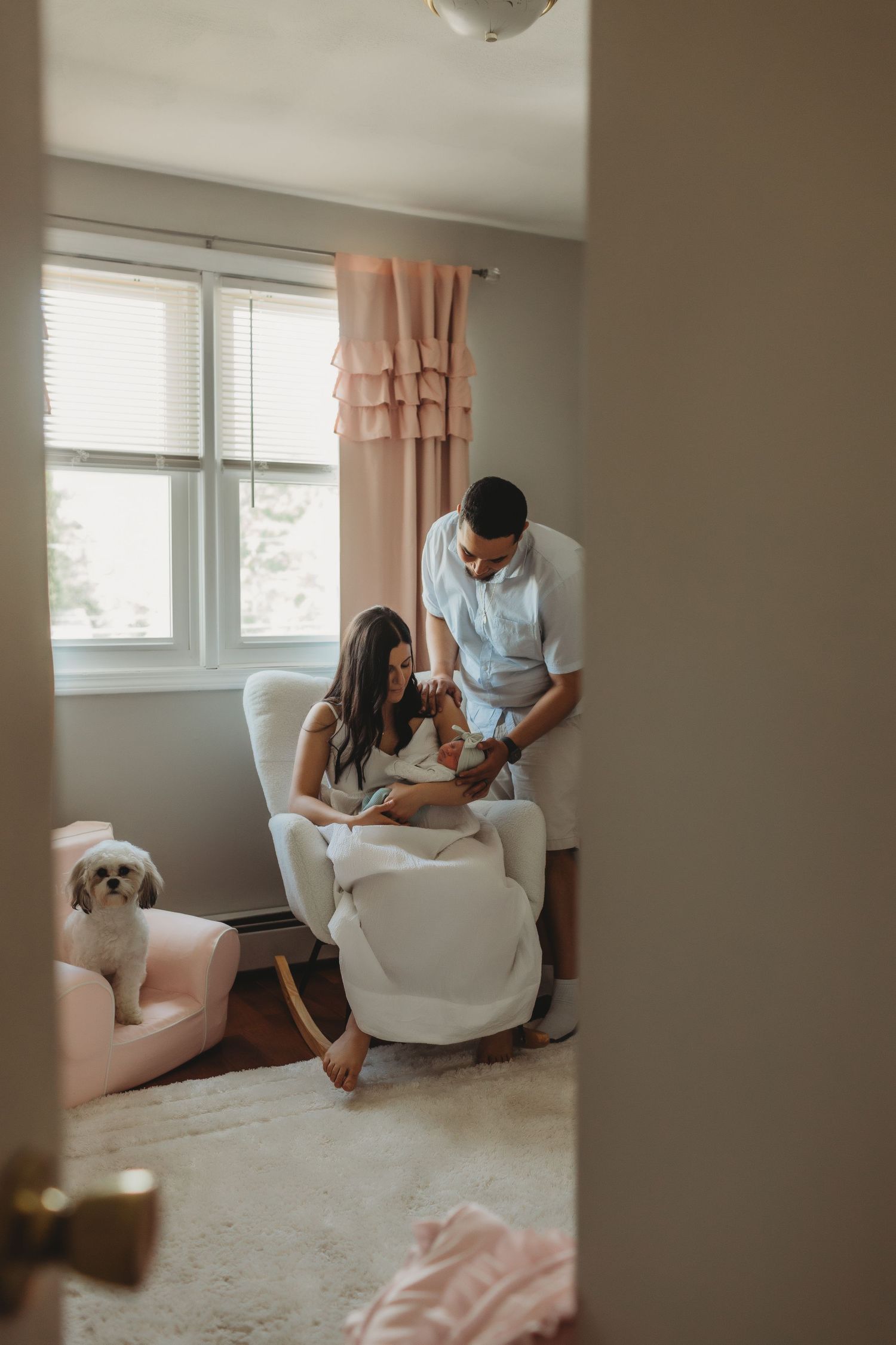 A couple shares a tender moment in a cozy corner of their home while their small white dog rests nearby.