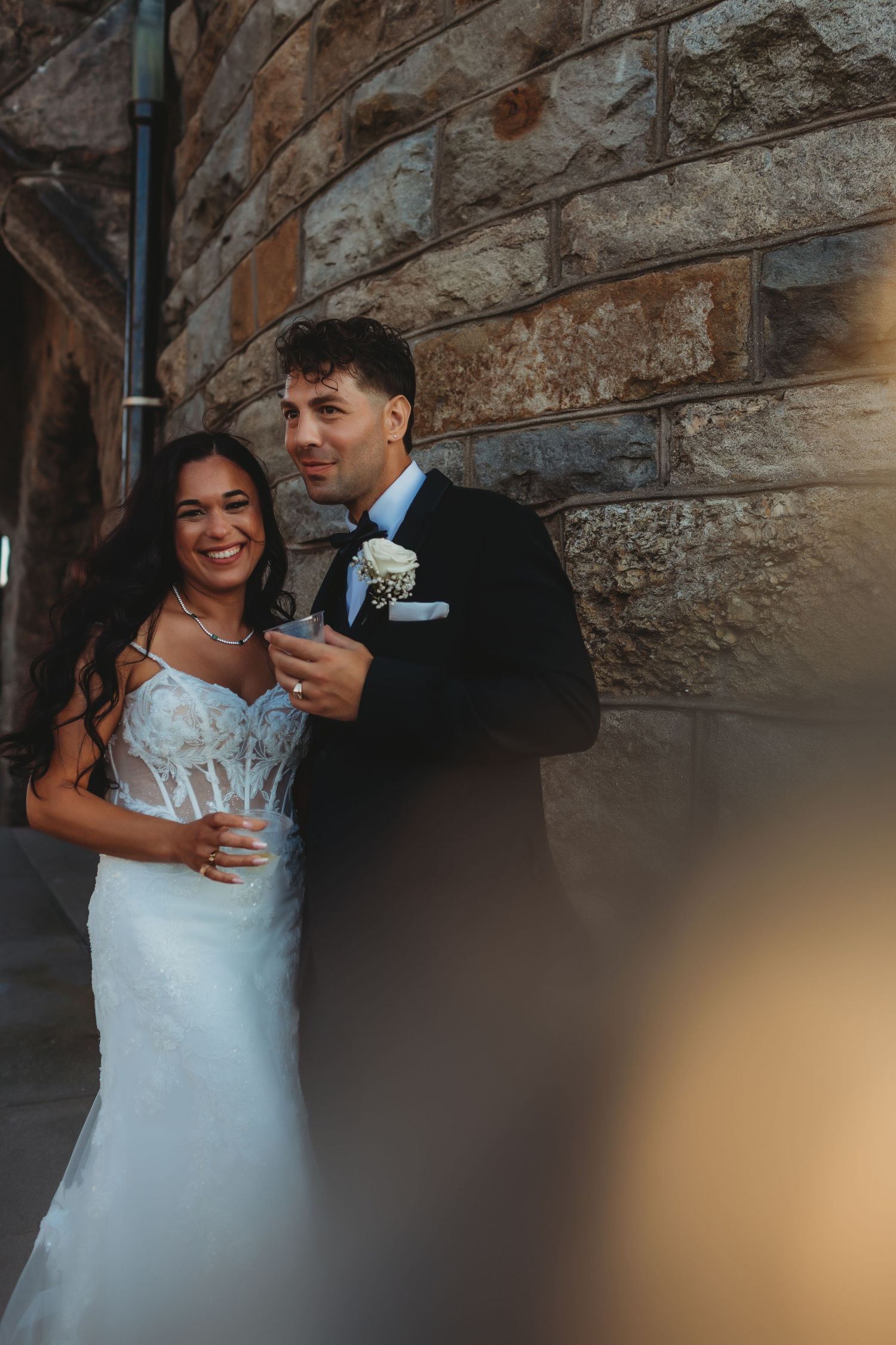 A couple shares an intimate dance moment in a rustic venue with exposed wooden beams overhead.