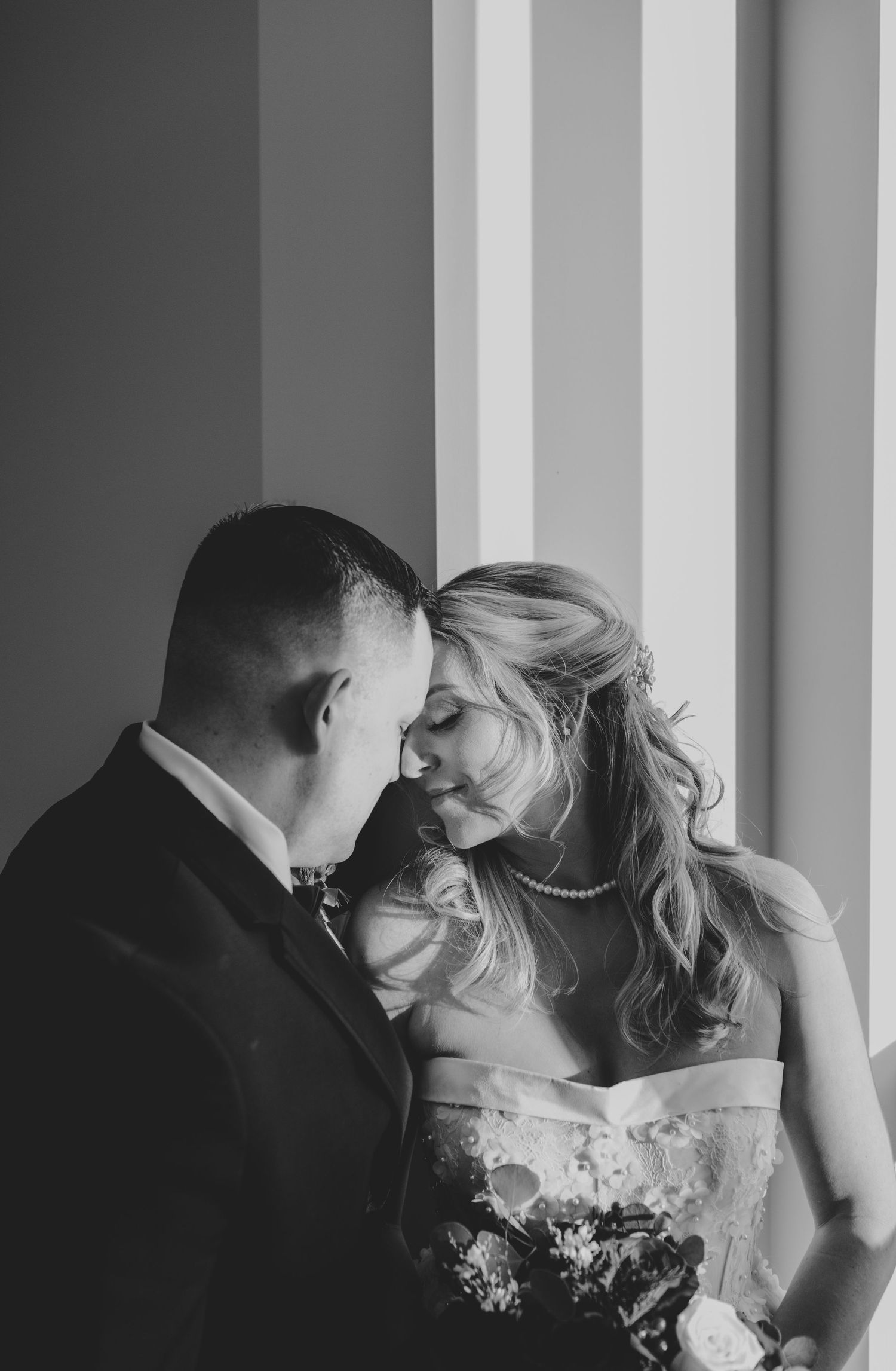 A romantic black and white wedding photo series showing intimate moments between a couple against a columned backdrop.