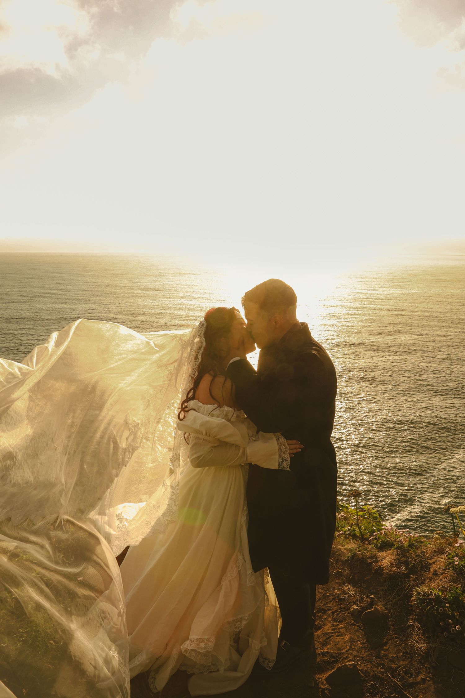 Couple embracing during their Oregon Coast elopement with waves and coastal cliffs behind them