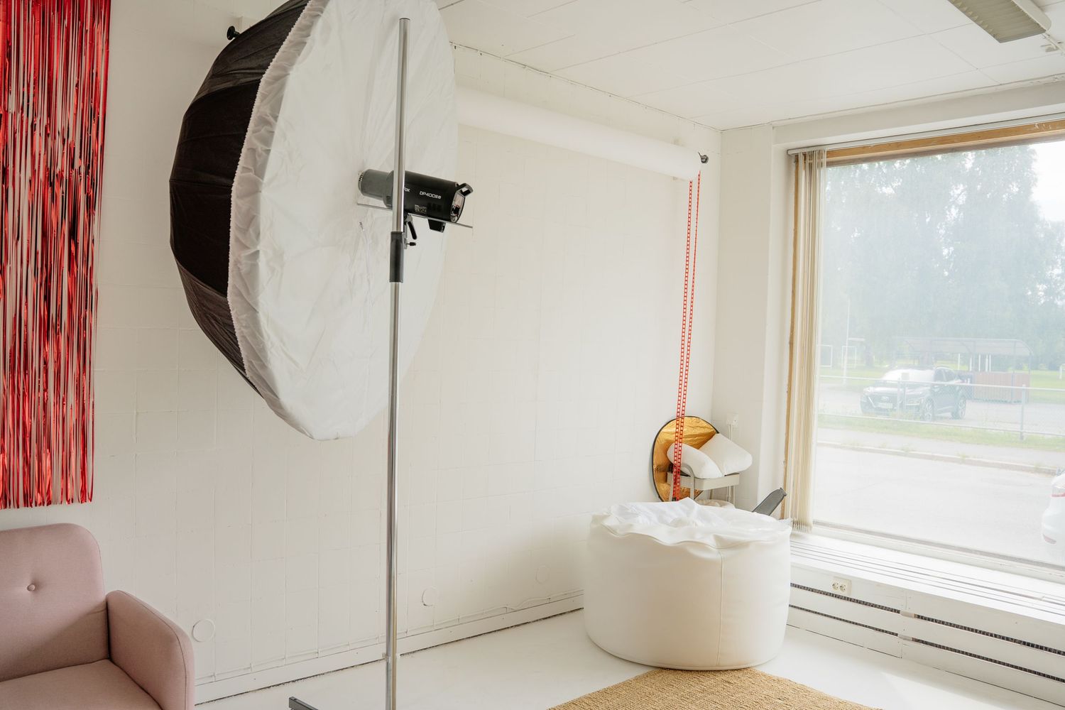 Professional photography studio with large softbox light, white bathtub, and natural window light for newborn sessions.