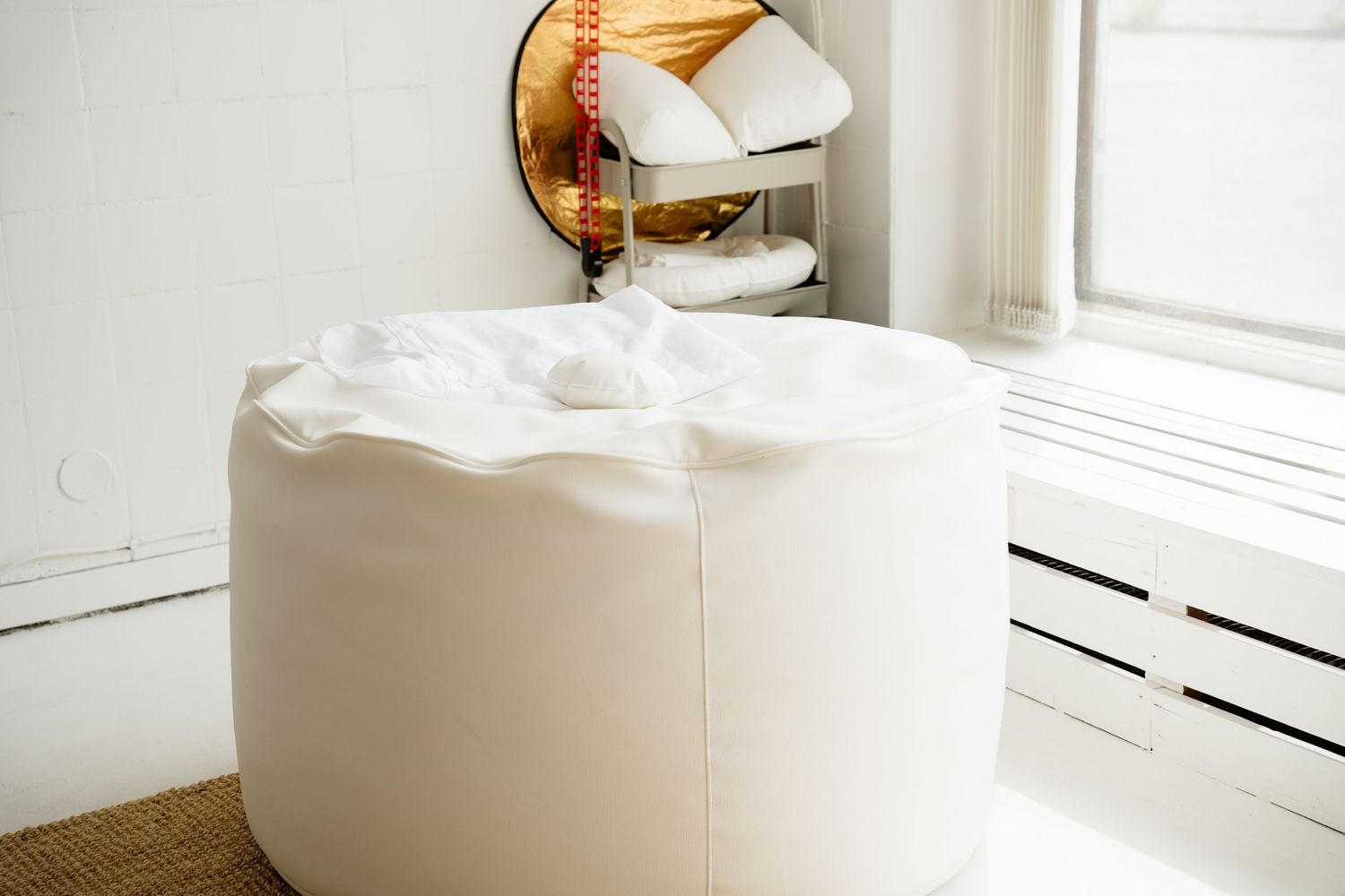 White leather bean bag chair with fluffy pillow top in a bright modern room with mirror and radiator.