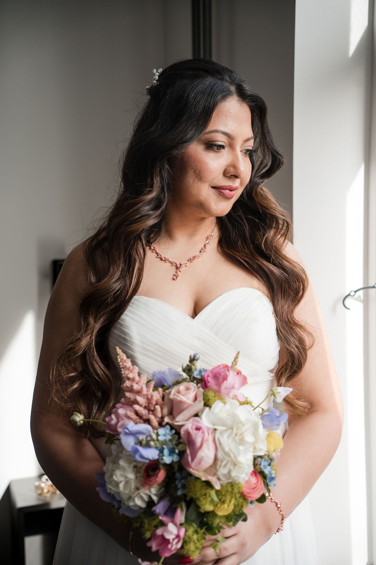 Romantic bridal portrait with colorful spring bouquet near a window.