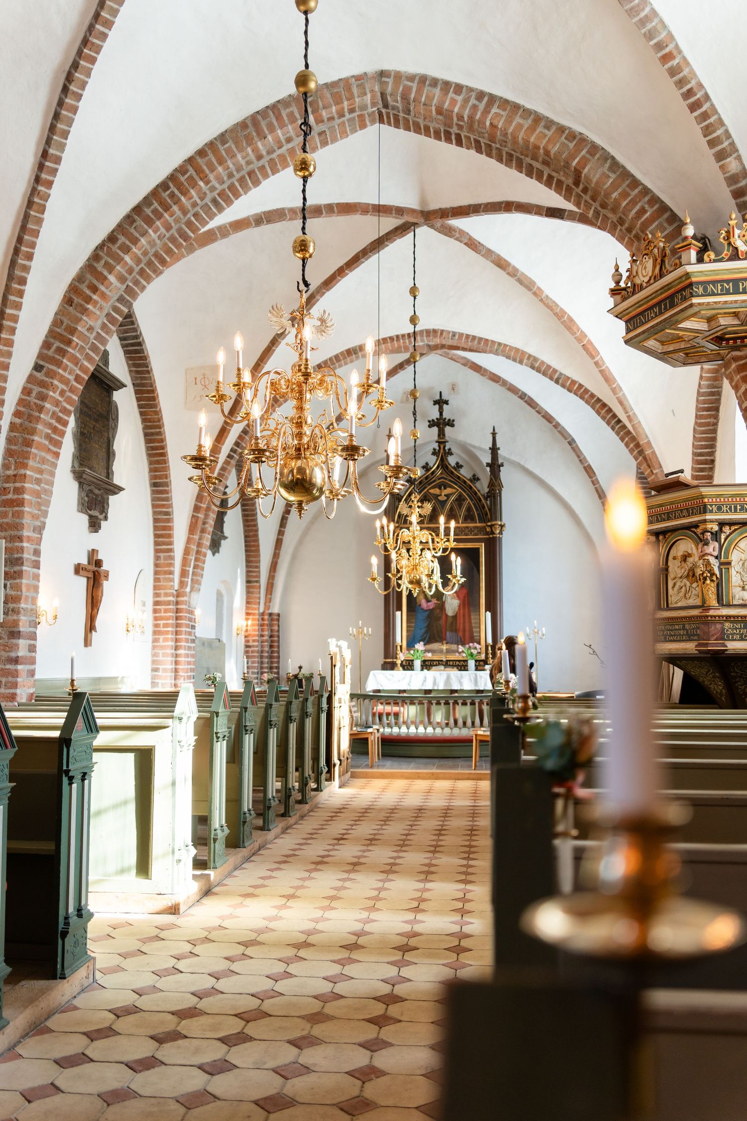 Historic church interior with vaulted brick ceilings and ornate chandeliers.