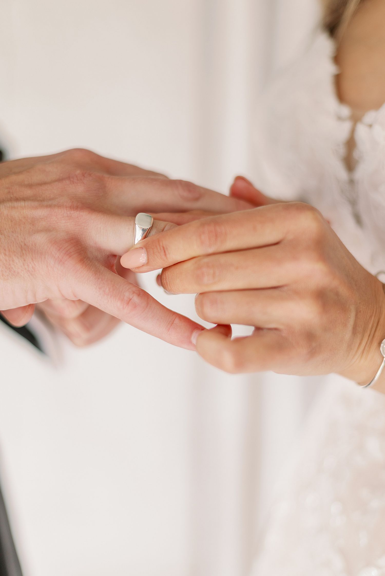 Close-up of delicate hands exchanging rings during a wedding ceremony.