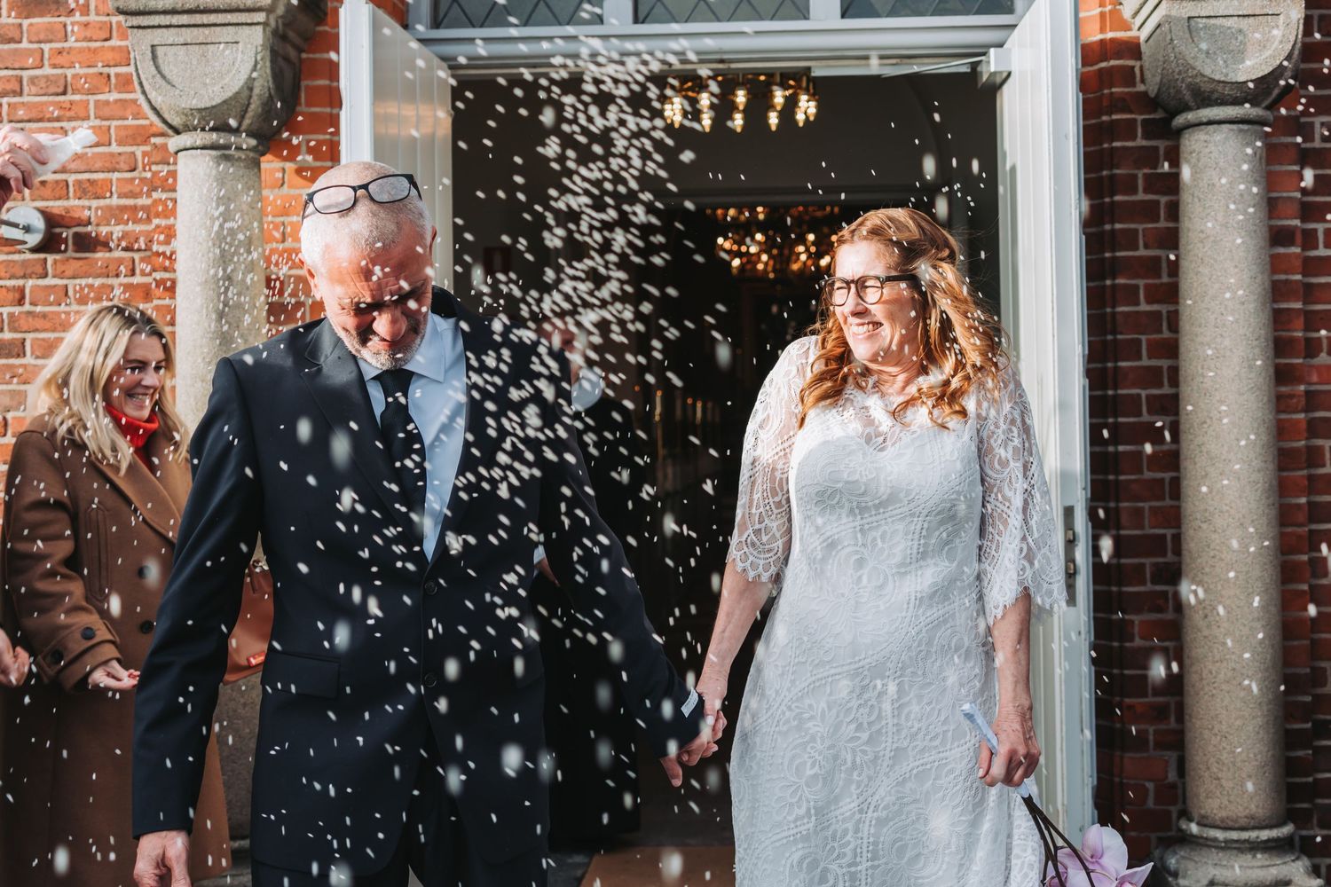 Wedding celebration moment with confetti flying outside a historic brick building.