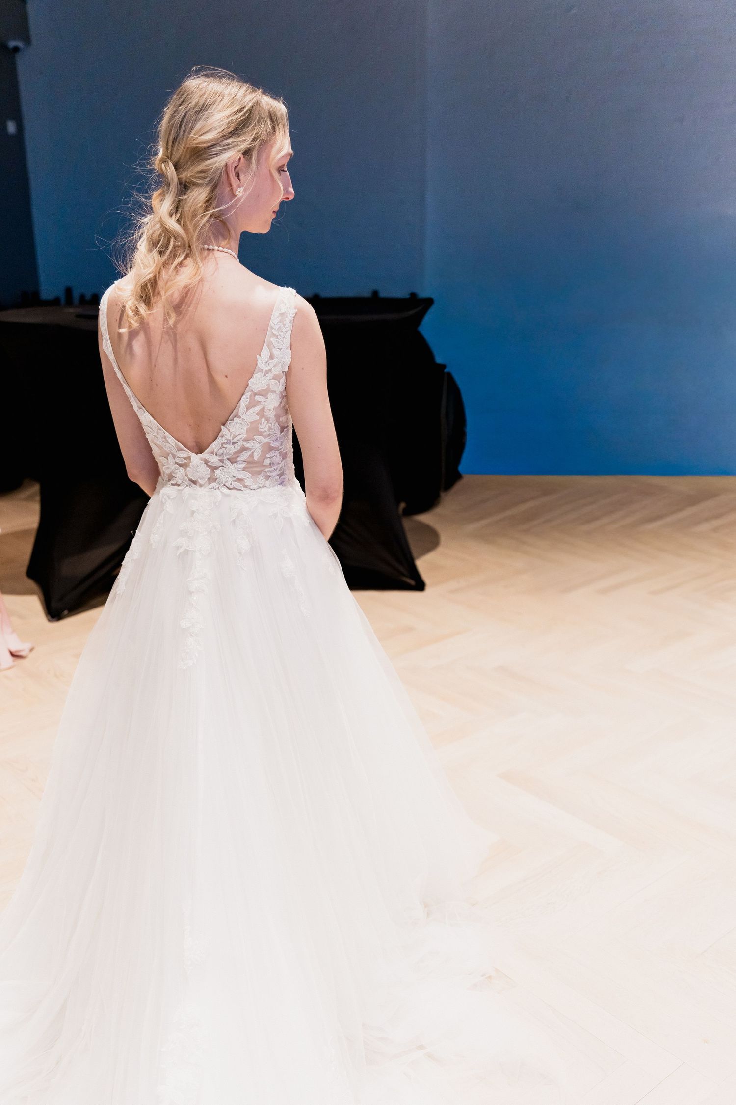Back view of a white wedding dress with lace details and flowing tulle skirt.