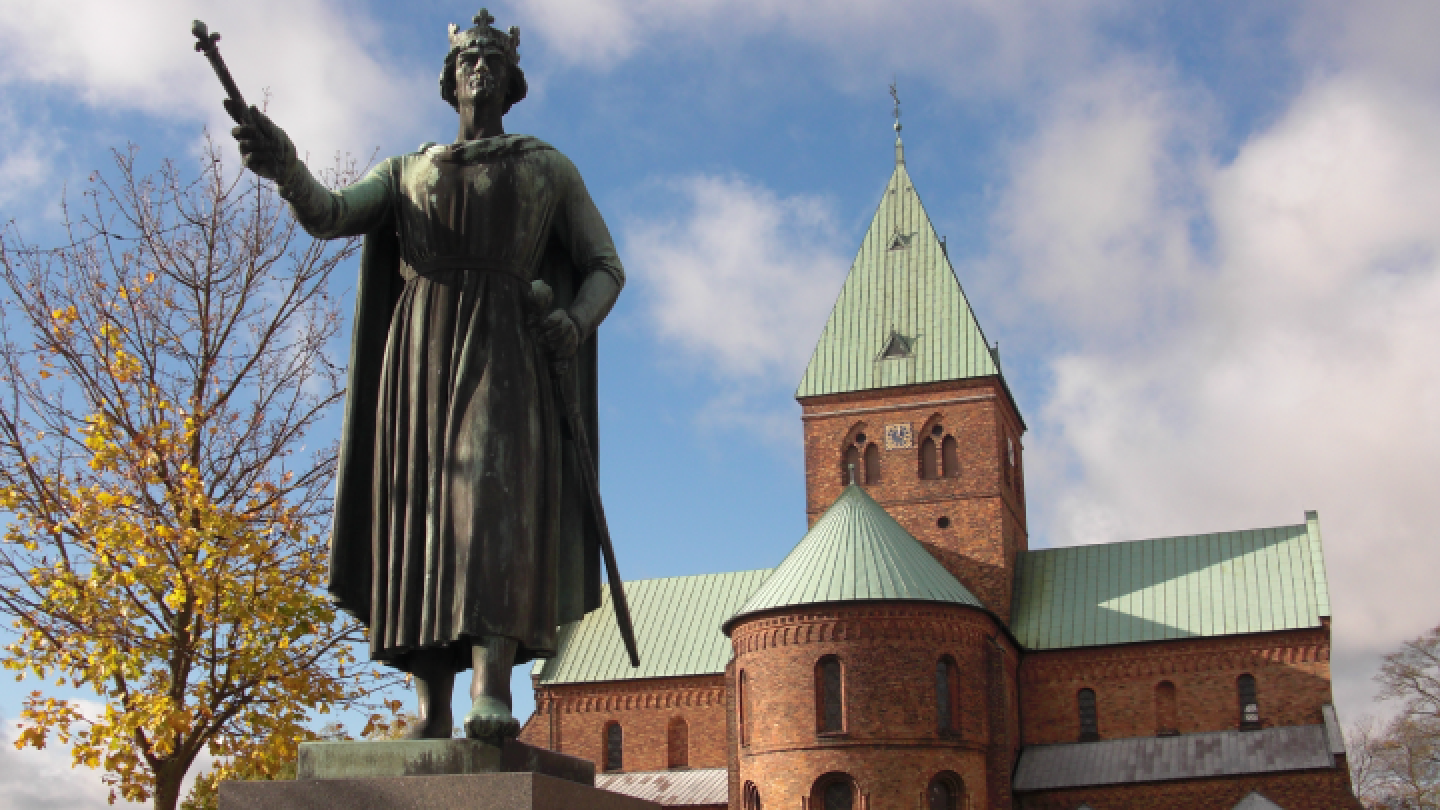 Historic statues and church spires against blue sky in European city.