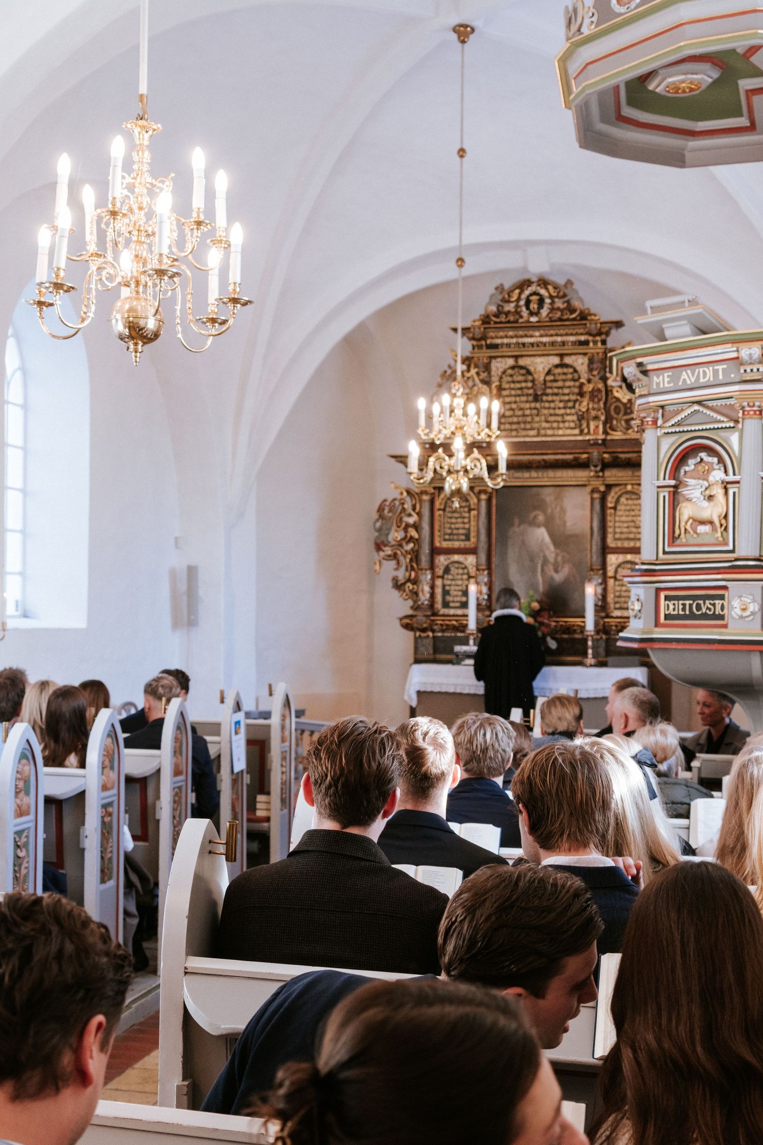 Interior of a traditional church with ornate chandeliers and vaulted ceilings during a ceremony.