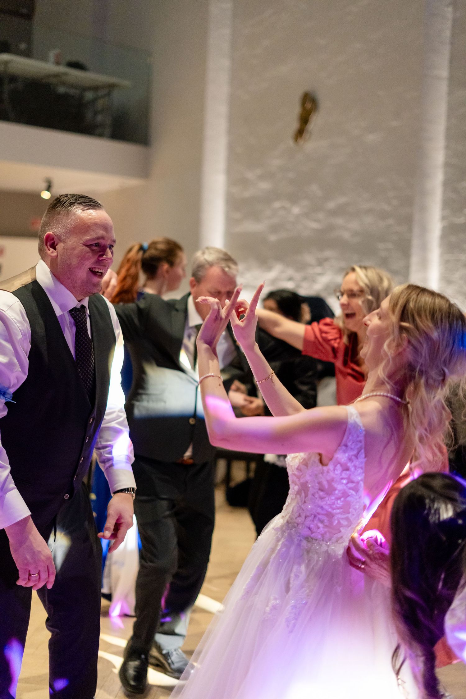 Bride and groom share a joyful first dance at their wedding reception surrounded by celebrating guests.