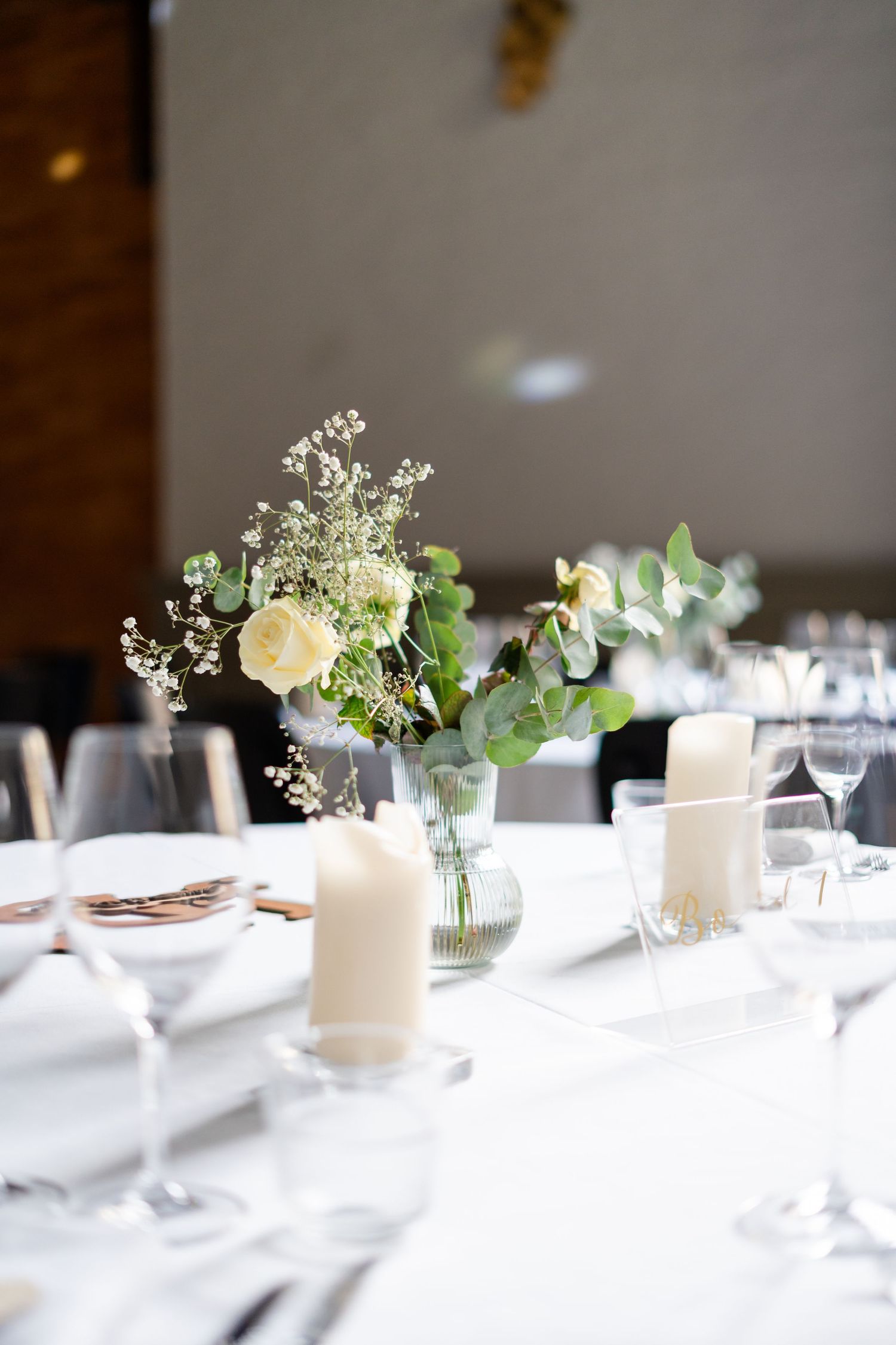 Elegant wedding table decorations with white flowers and greenery in glass vases.