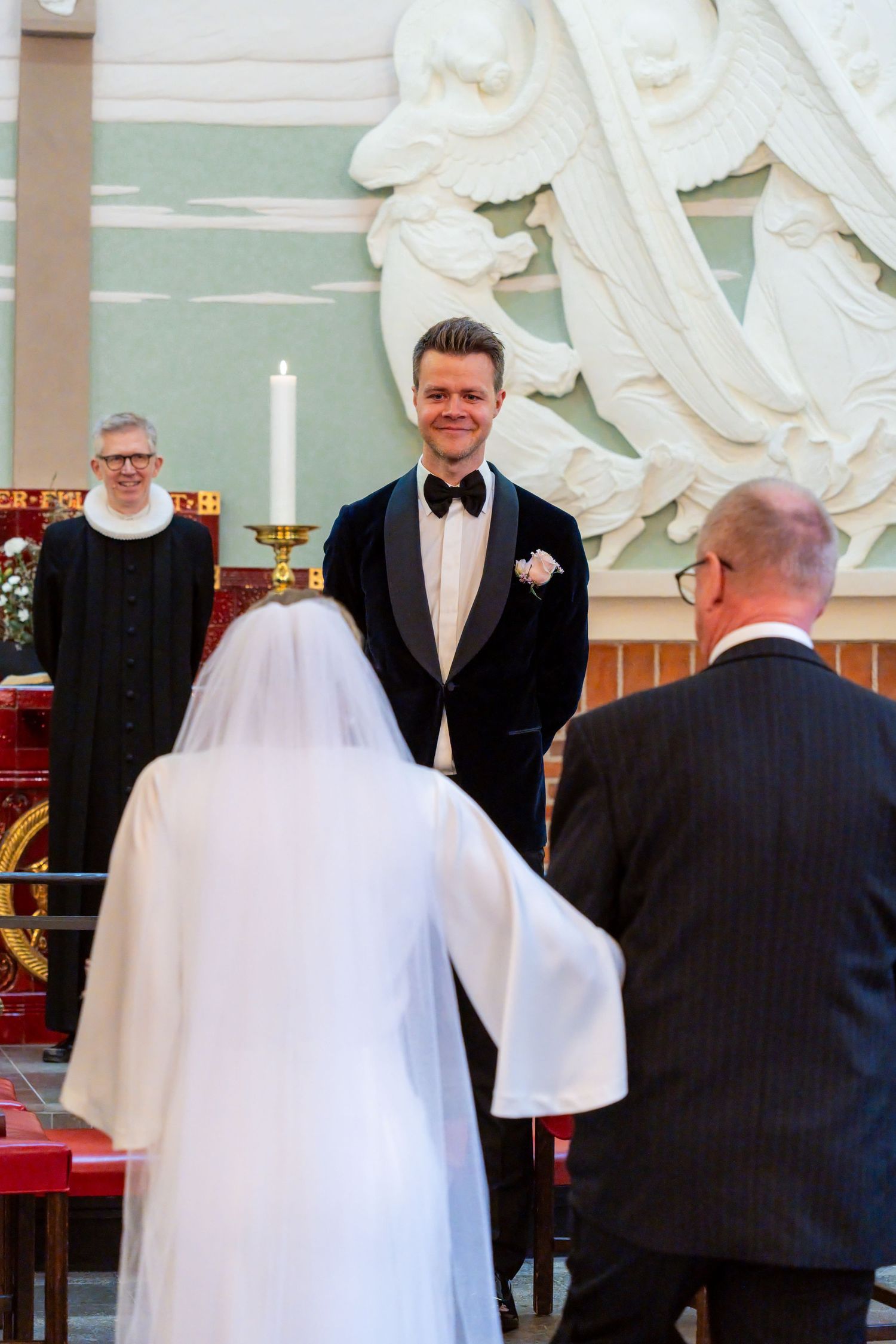 A bride and groom stand at the altar during their wedding ceremony, with a minister presiding over the event.