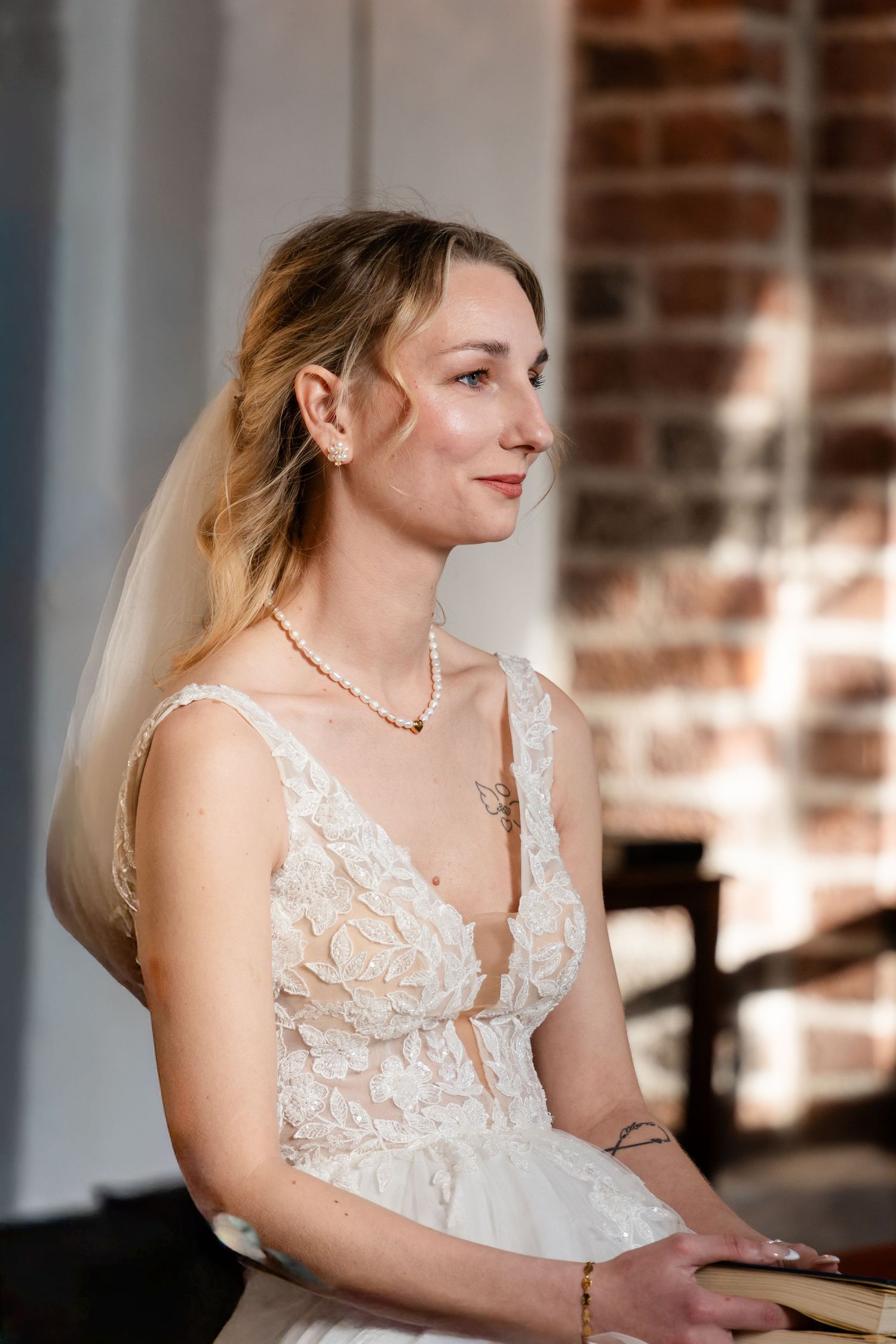Elegant bridal portrait showing lace bodice details against exposed brick wall.