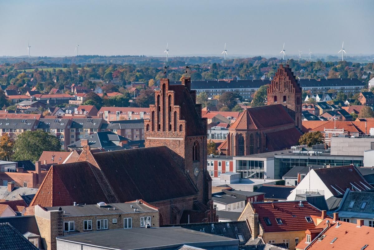 Panoramic cityscape view of red-roofed buildings and church spires.