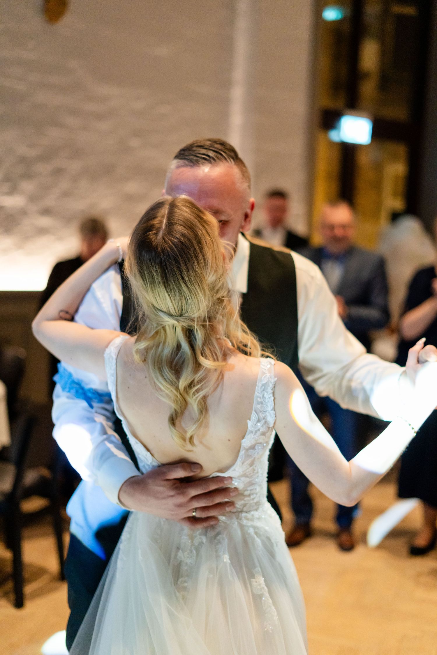 Couple sharing their first dance at wedding reception in elegant white dress.