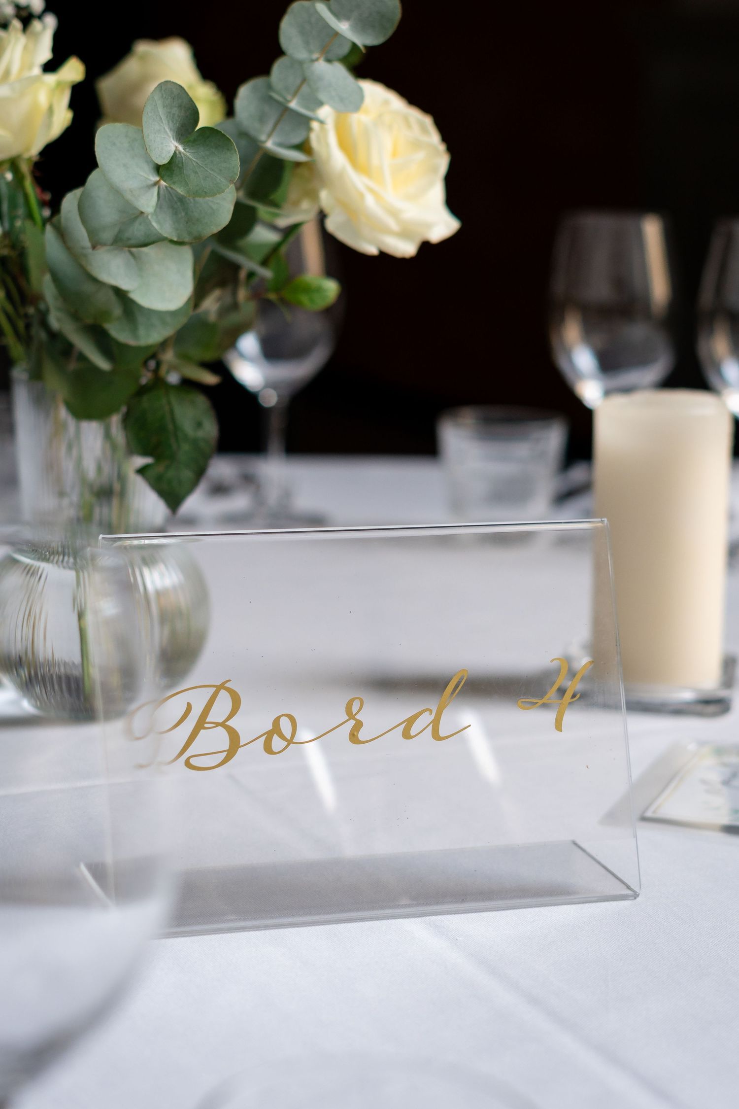 Wedding table number 'Bord 4' displayed with eucalyptus and white roses.