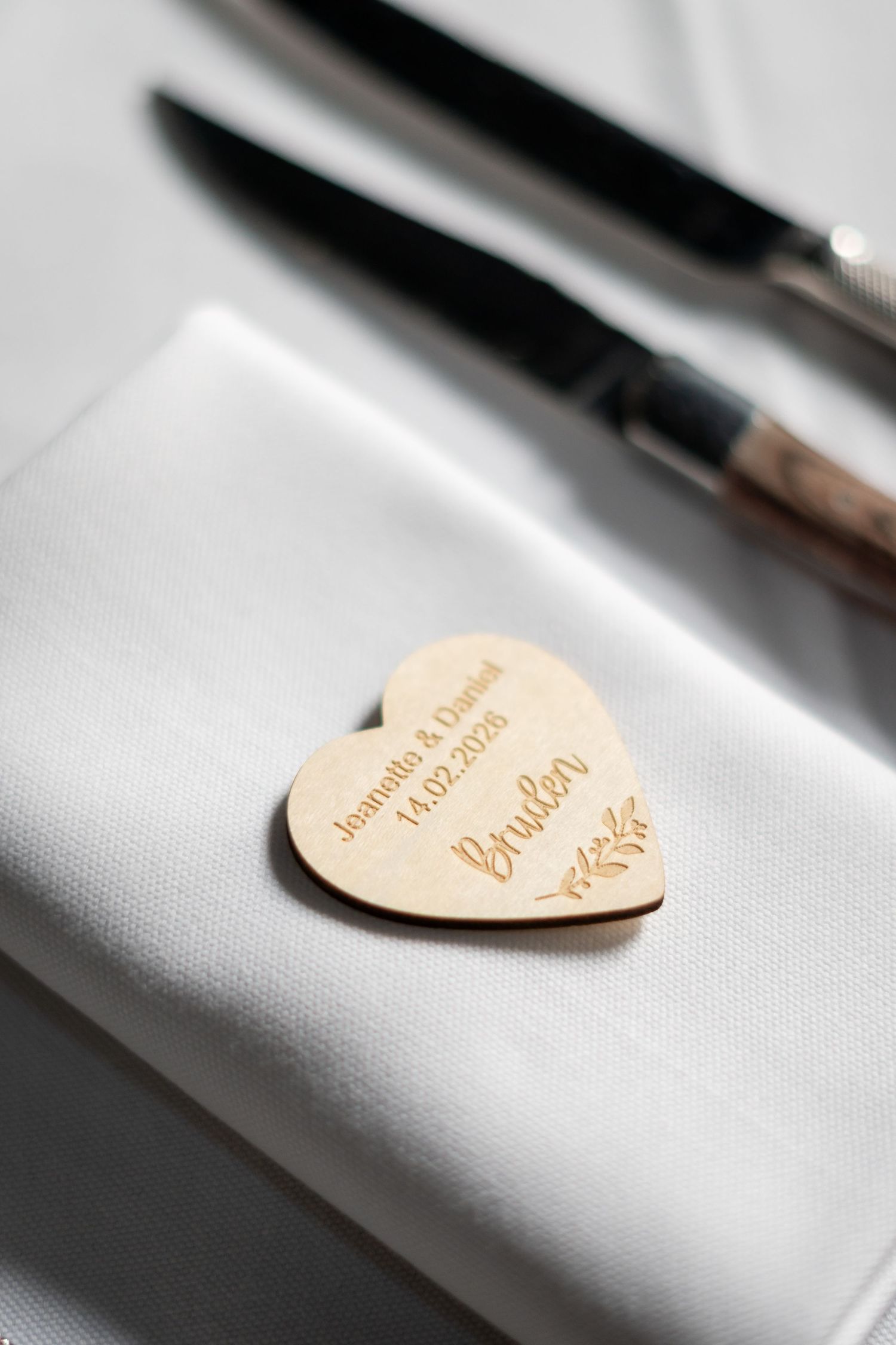 Wooden heart-shaped place card on white linen tablecloth.