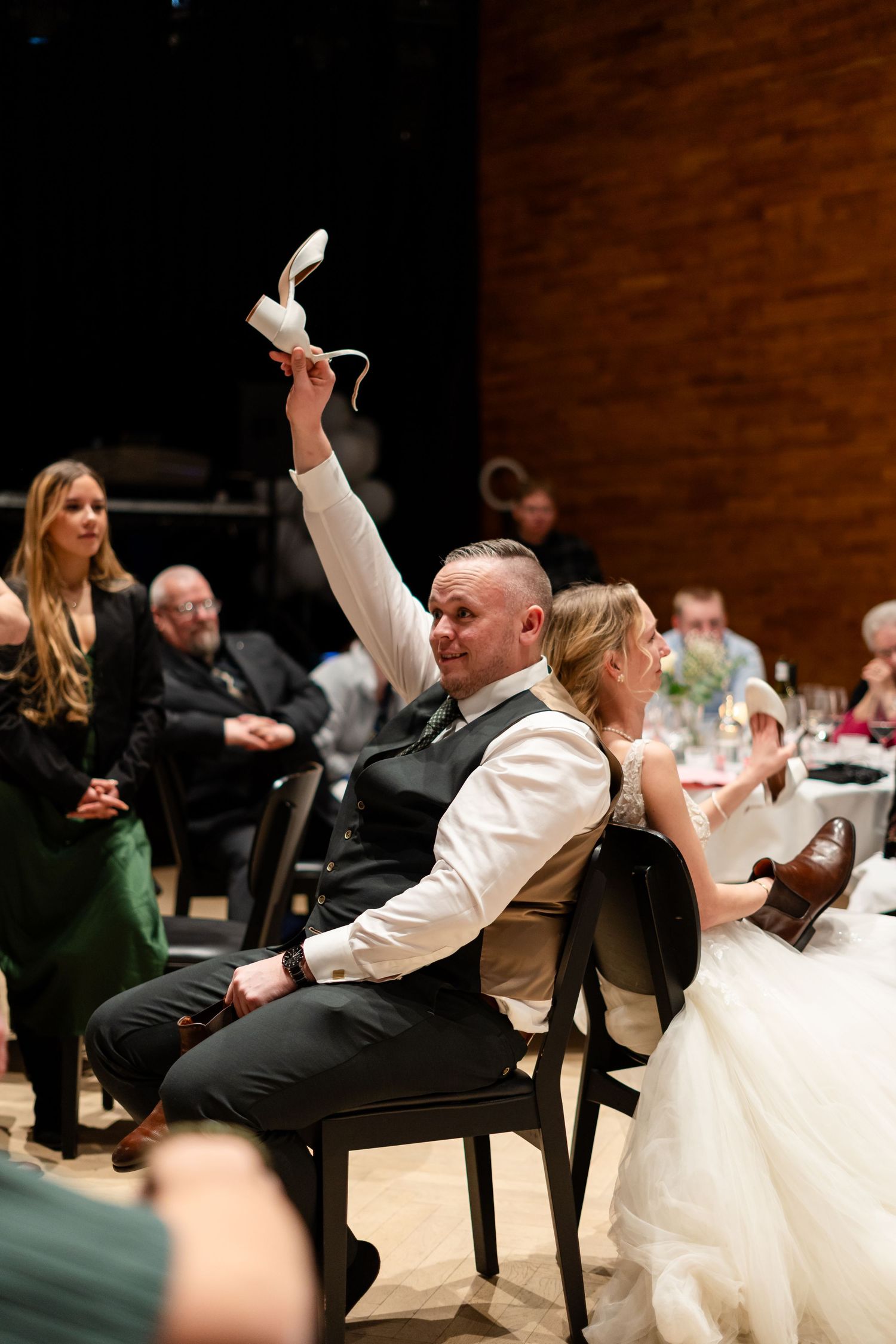 Wedding reception game with guests reaching under chairs during a fun activity.