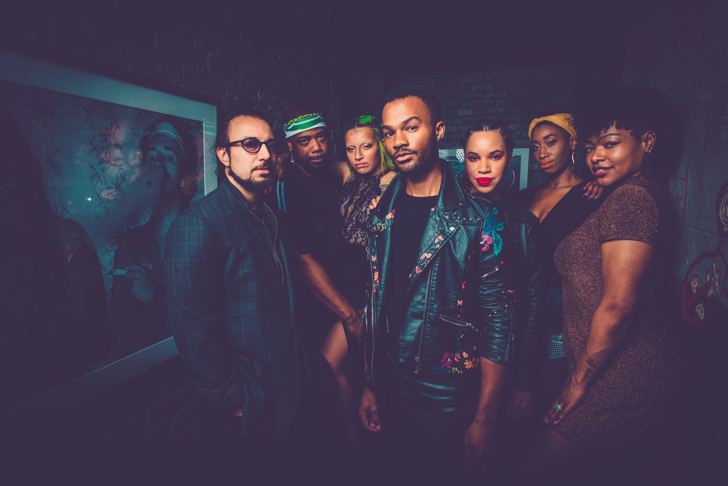 People dancing and socializing at a dimly lit nightclub with atmospheric lighting and a crowded dance floor.