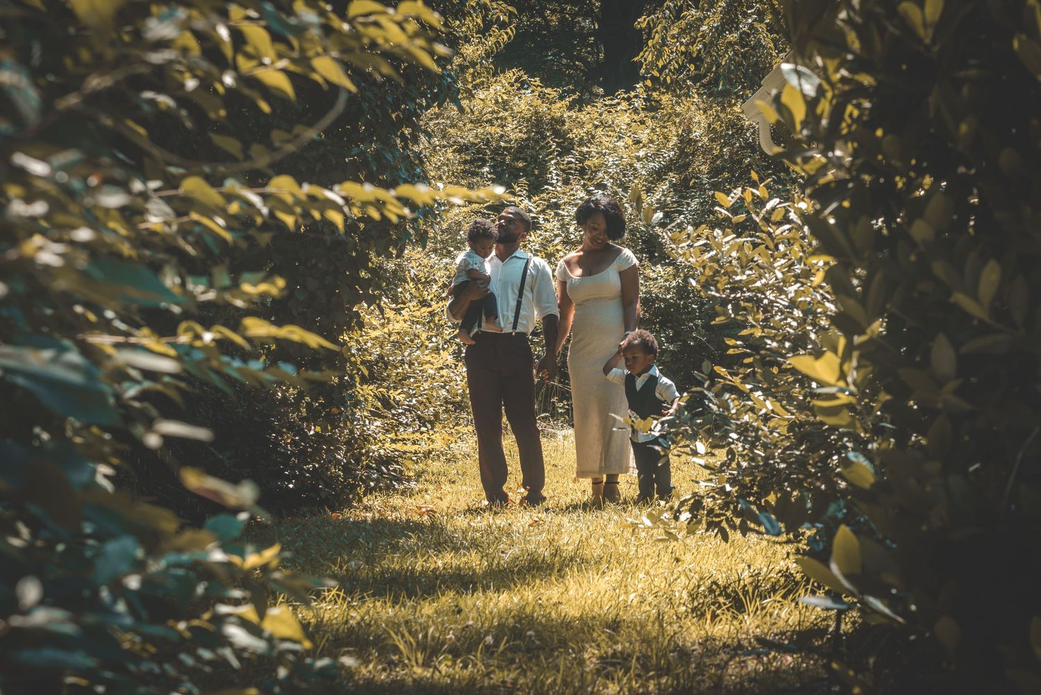 A couple walks together on a sunlit forest path with golden light filtering through autumn trees.