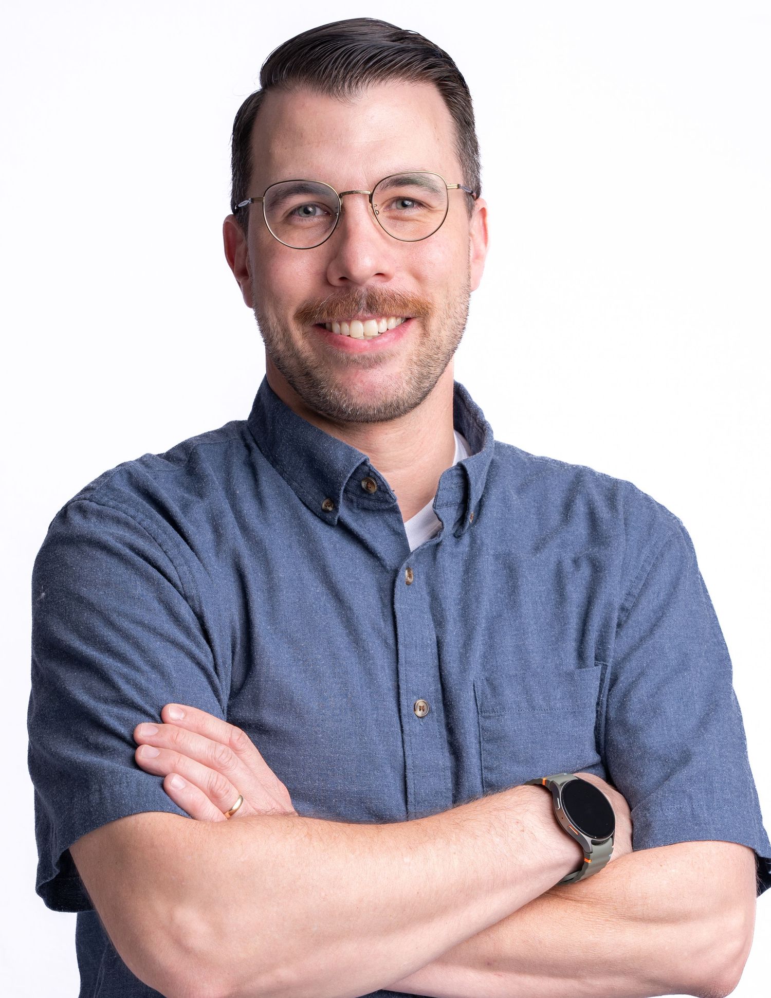A person wearing glasses and a blue shirt smiles while posing in four similar headshots against a white background.