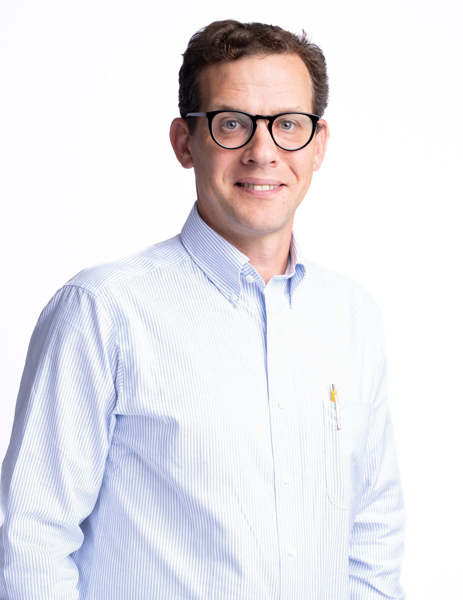 Professional headshot of person wearing a light blue striped button-down shirt and glasses stands against a white background.