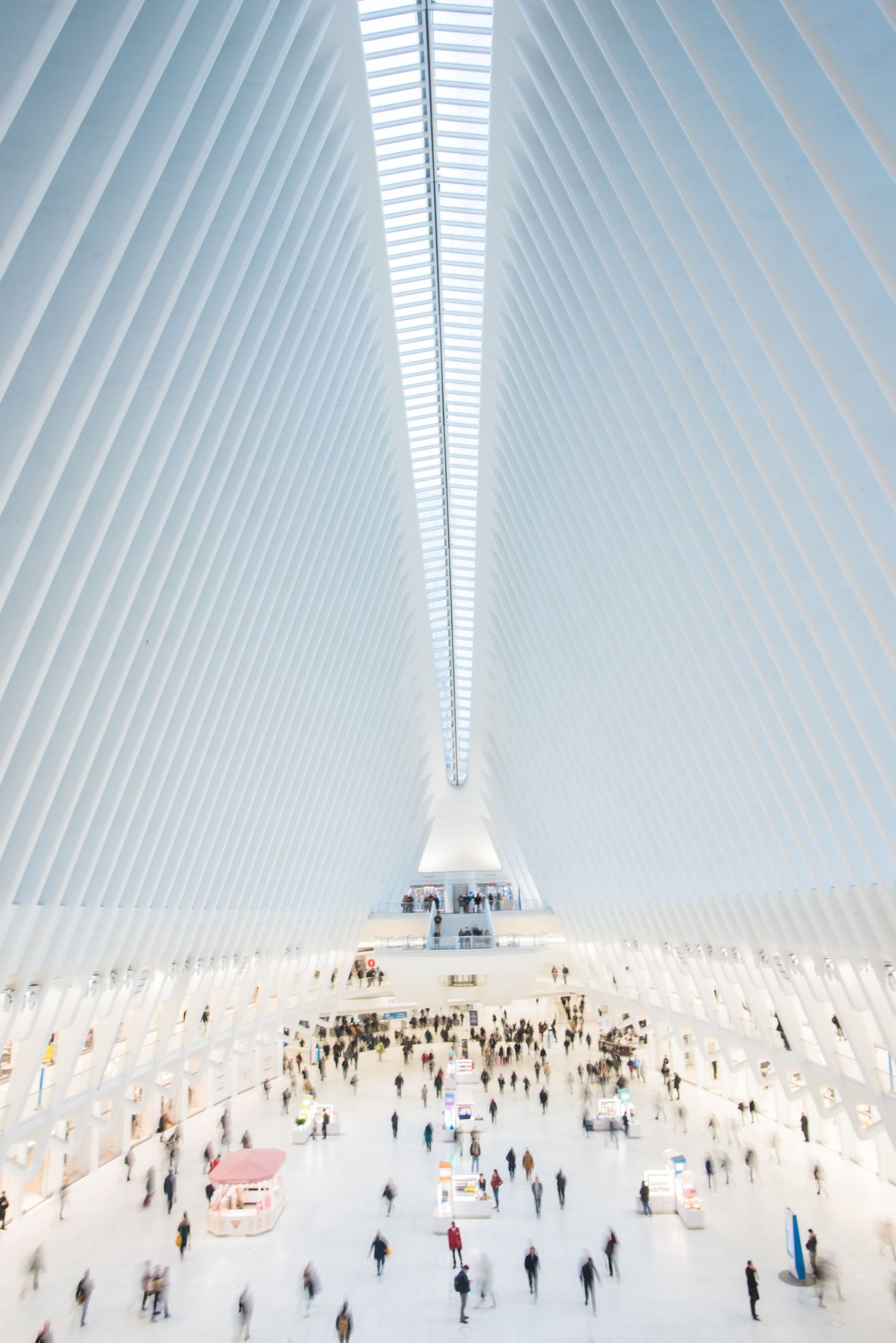Modern white architectural interior with ribbed ceiling and crowds of people below.