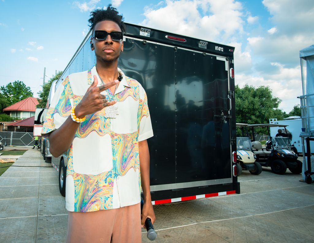 A colorful Hawaiian shirt is worn while standing next to a black commercial truck on a sunny day.