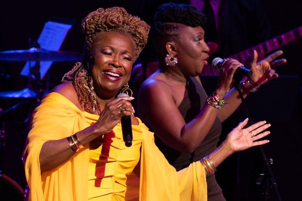 Jazz singers in yellow robes performing passionately on stage with dramatic lighting.