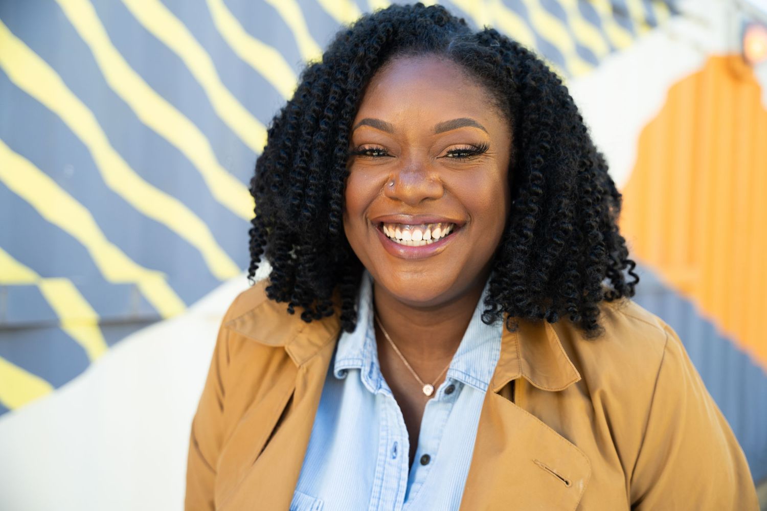 A warm smile radiates against a vibrant yellow and blue patterned background.