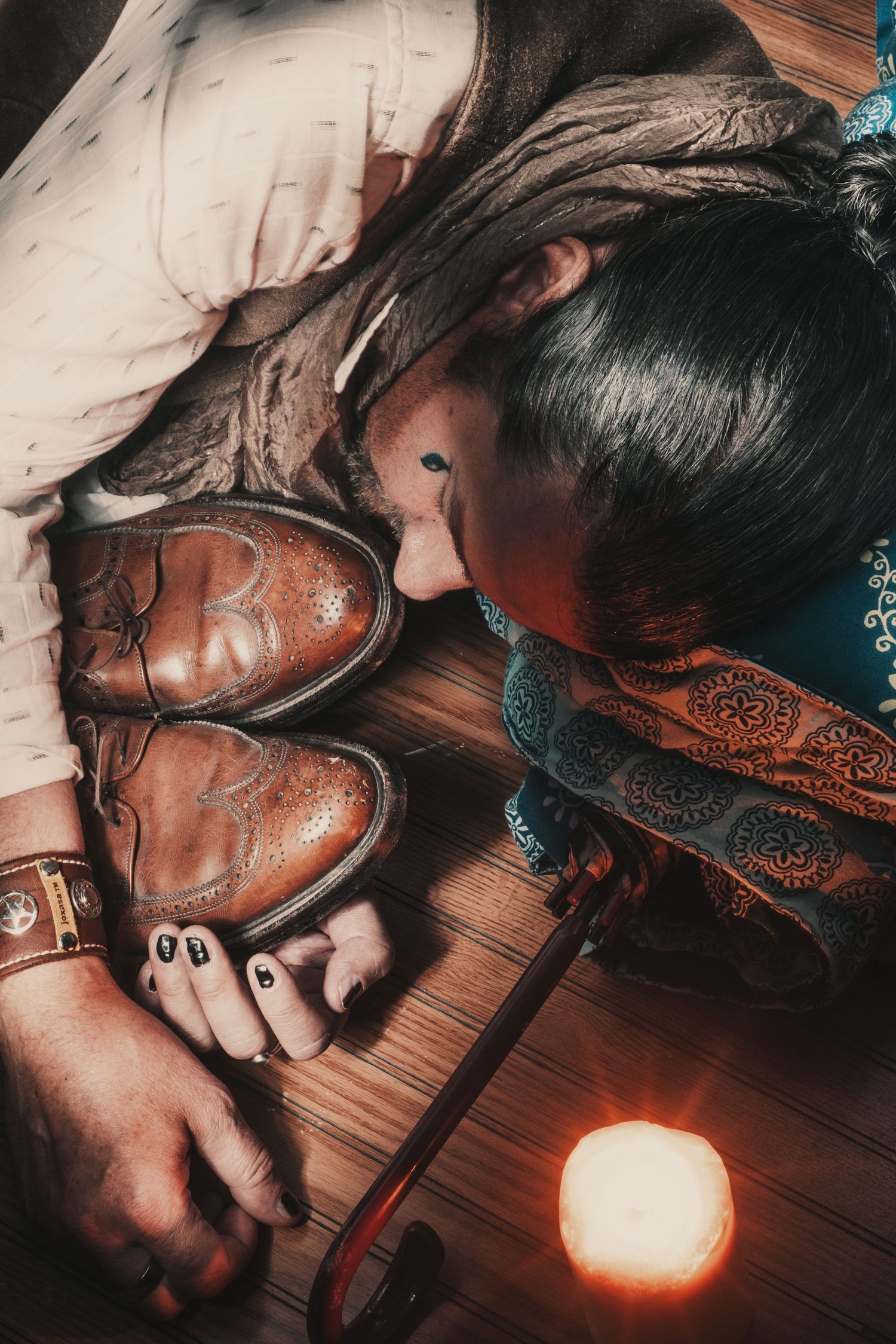 Person sleeping with brown leather boots by candlelight with vintage styling and moody atmosphere.