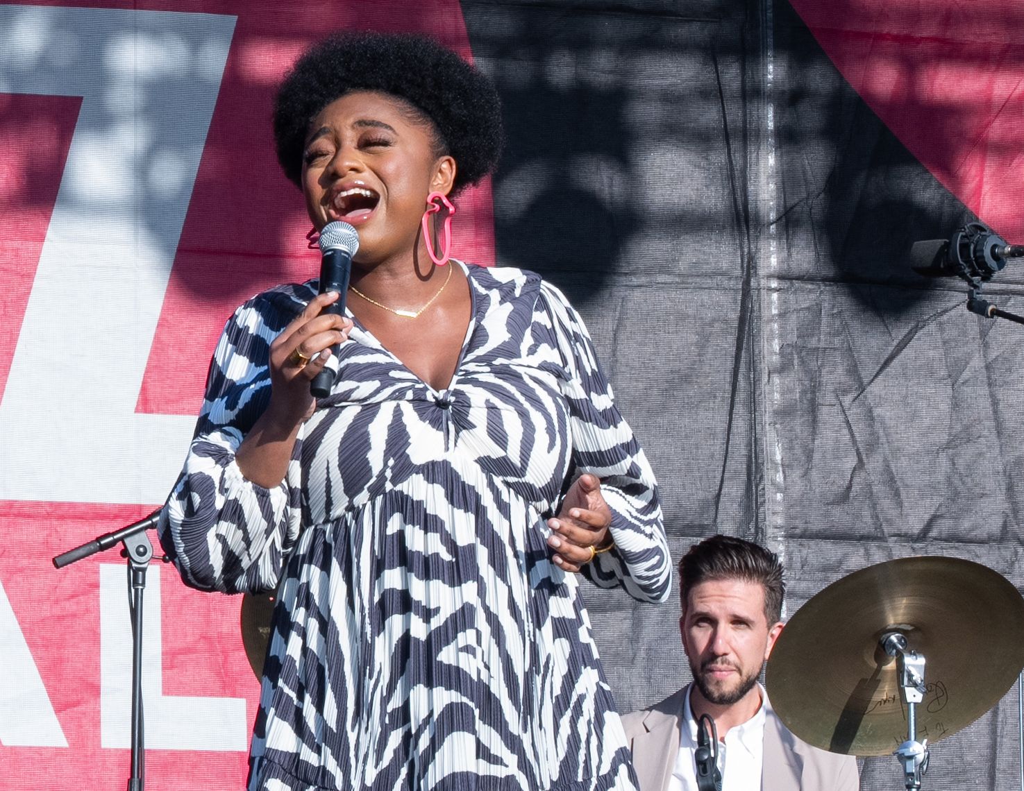 Jazz singer performing energetically on stage wearing a black and white patterned outfit.