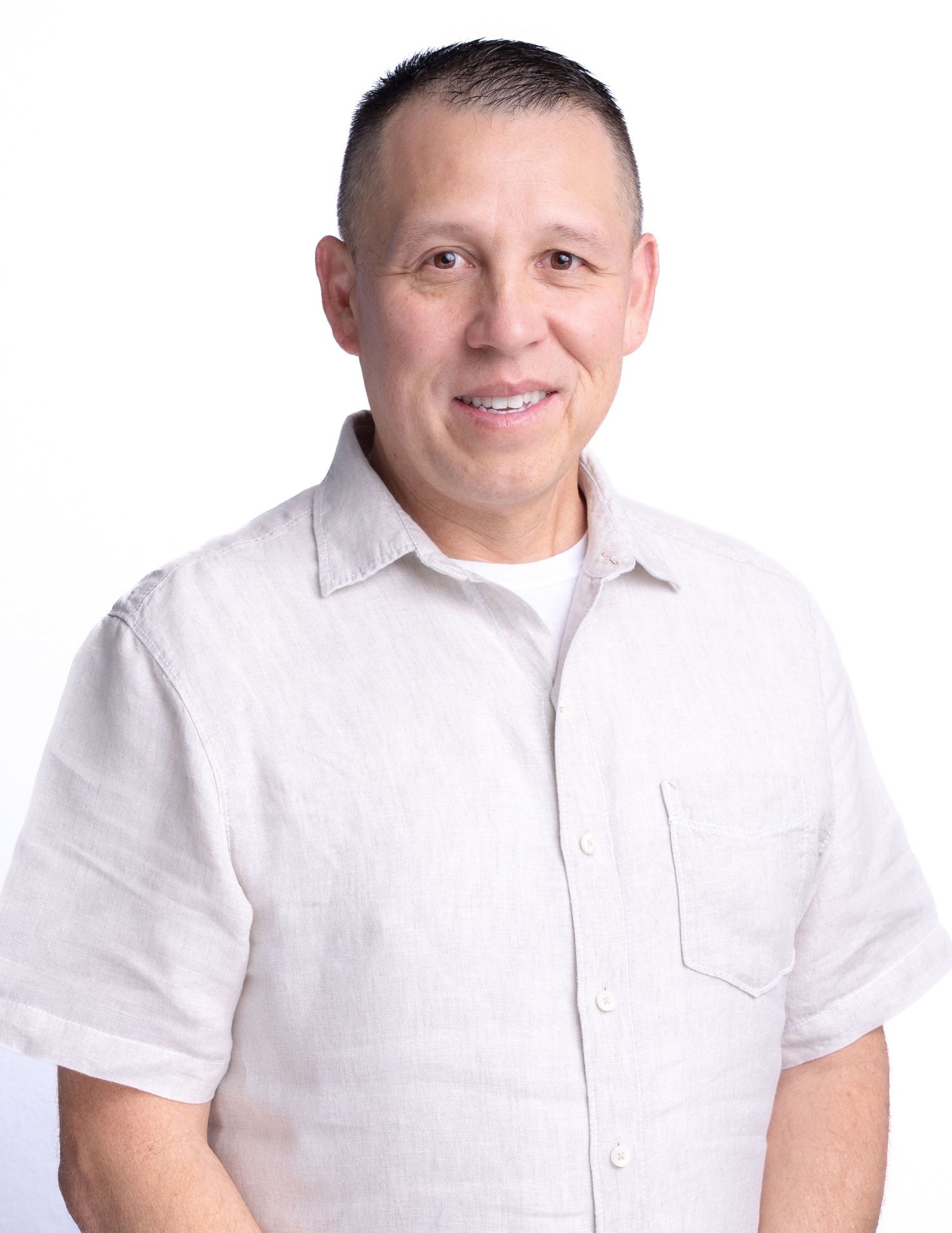 Professional headshot of person wearing white shirt smiling against a white background.