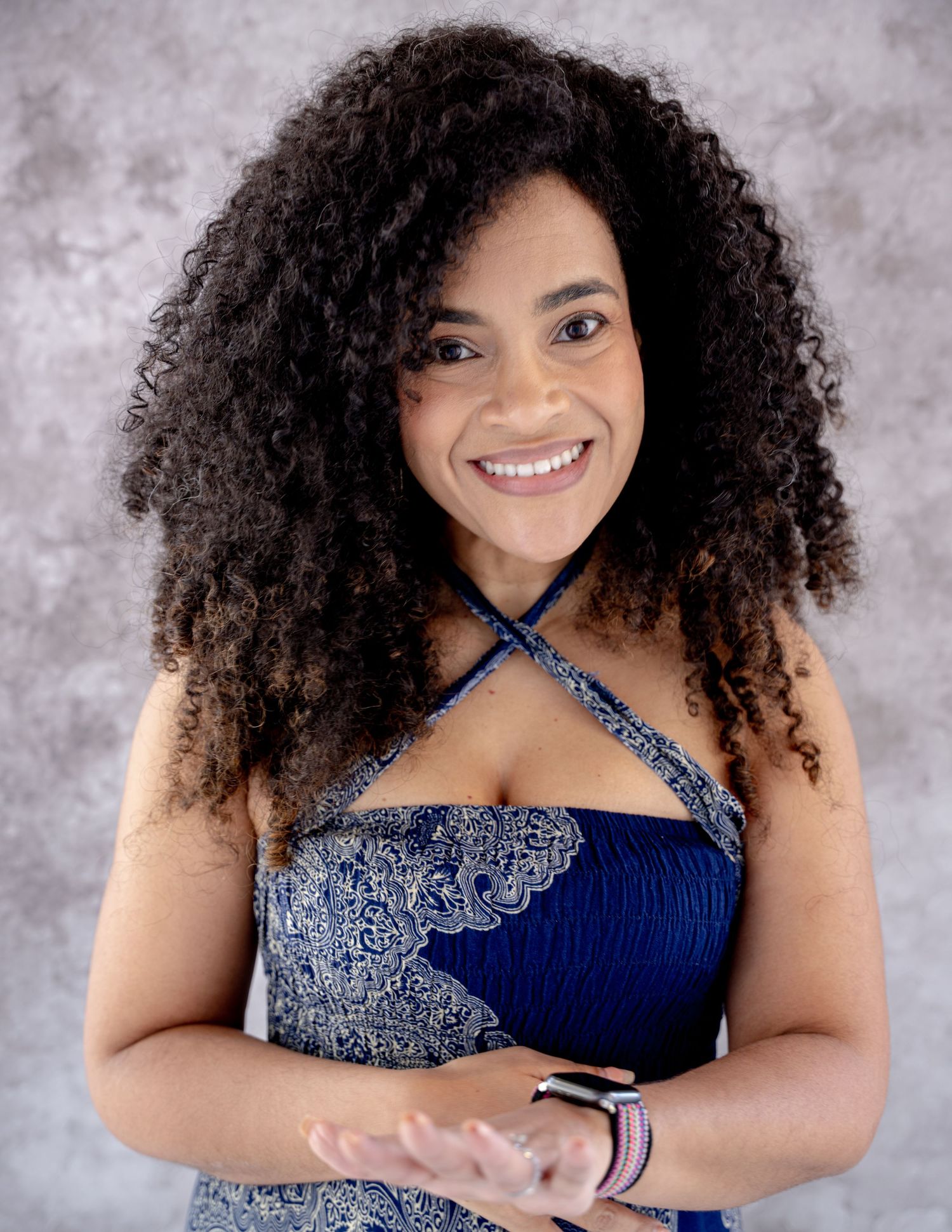 A series of five studio portraits showing a smiling figure with curly hair wearing a navy and silver dress.